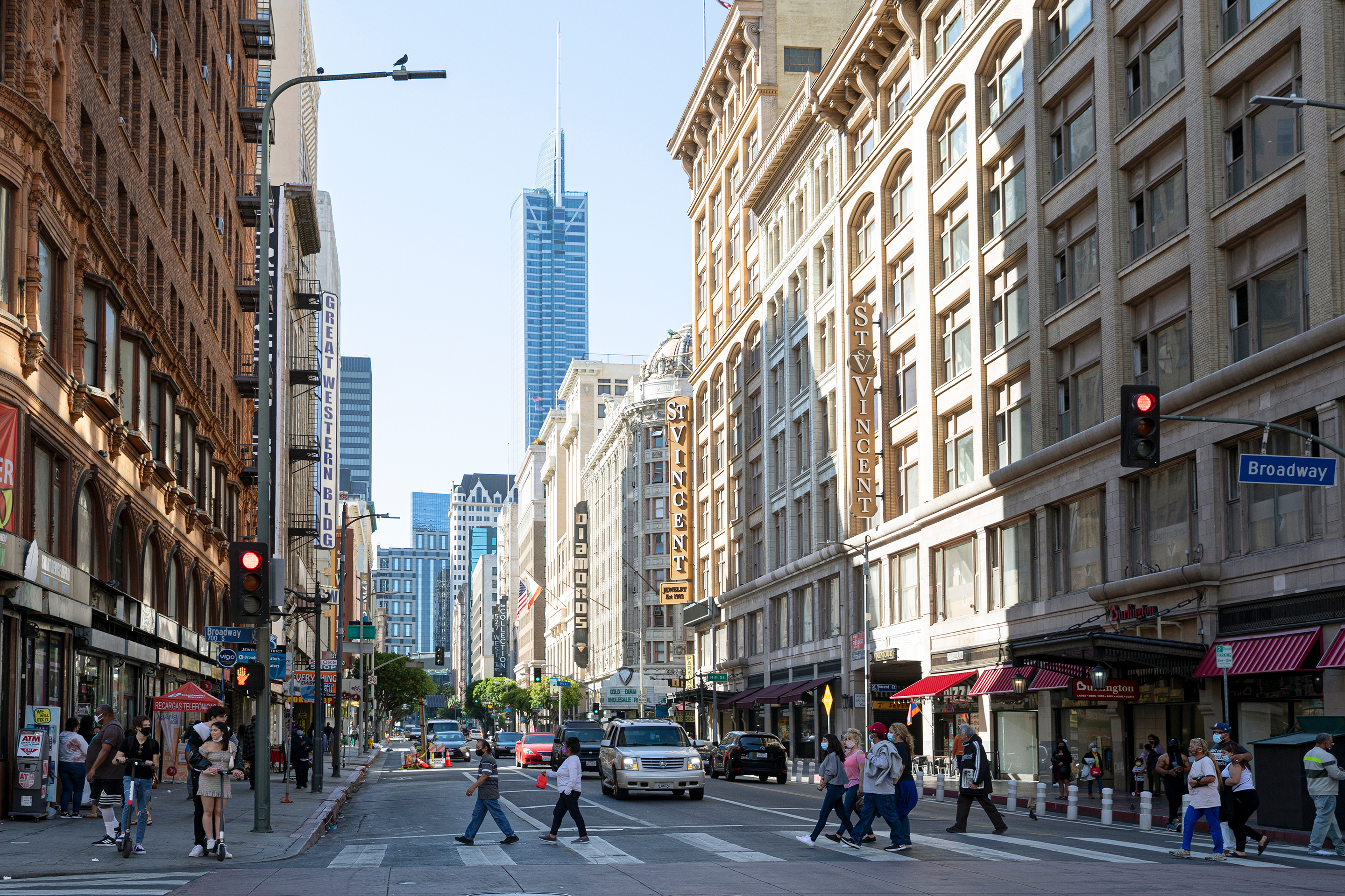 eople wearing protective face masks due to COVID-19, crossing the street in downtown LA.