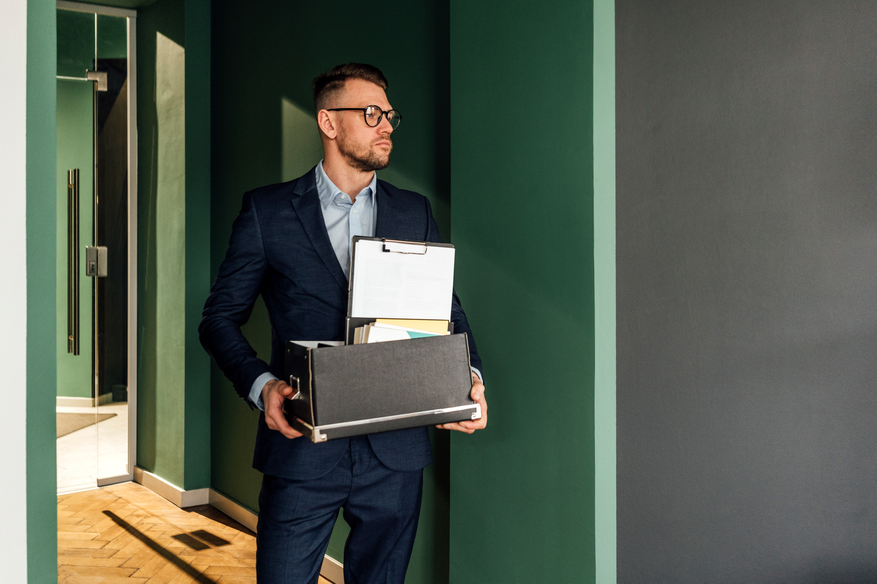 C Suite businessman leaving office with box of belongings.
