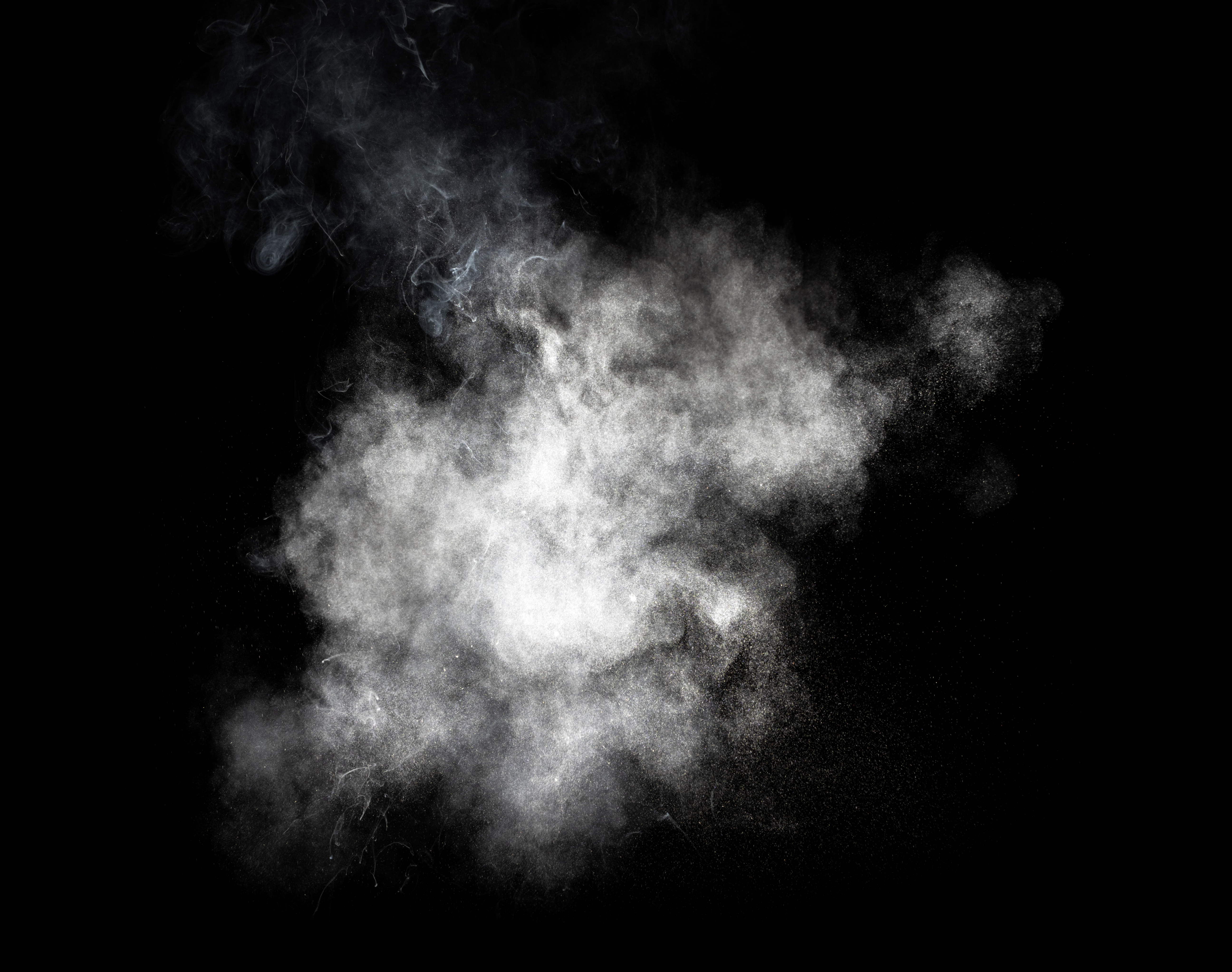 Explosion of a cloud of particles of smoke of white color on a black background.