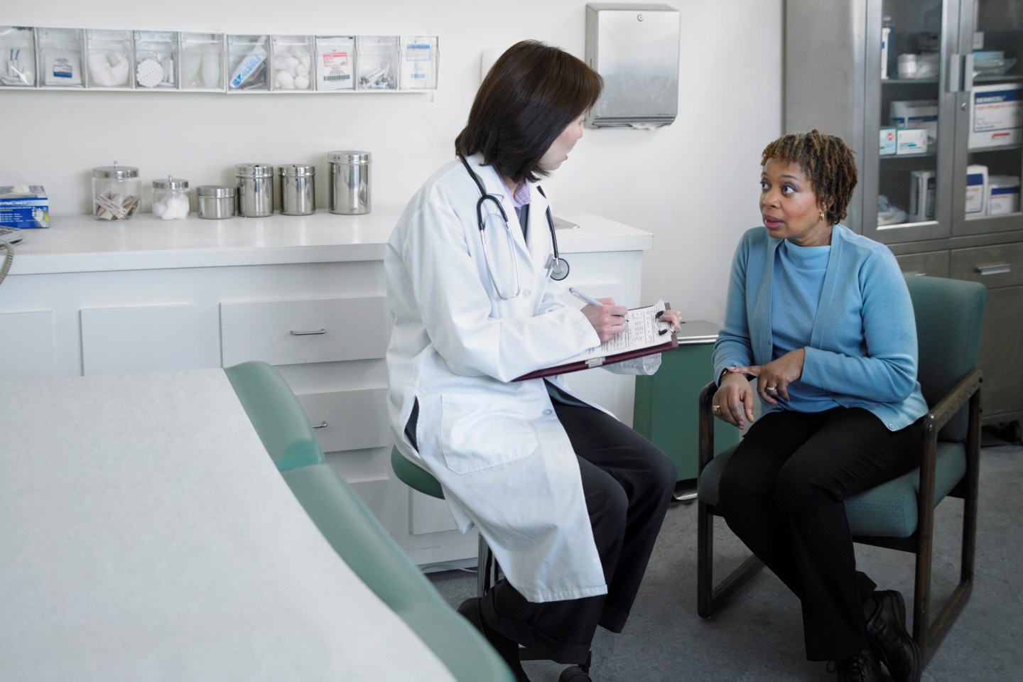woman sitting in a chair talking with a doctor