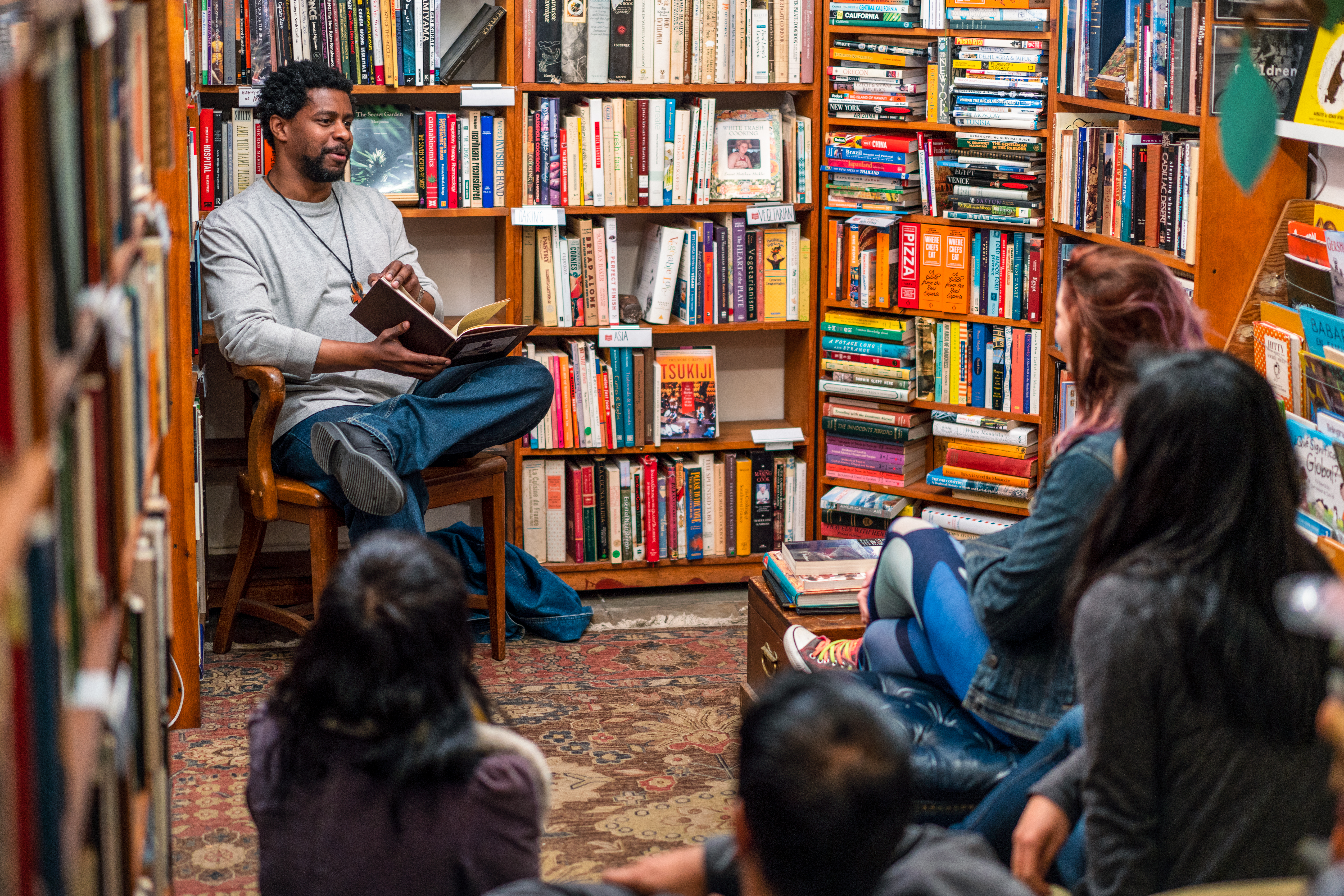 A man reads to a group of people in a bookstore