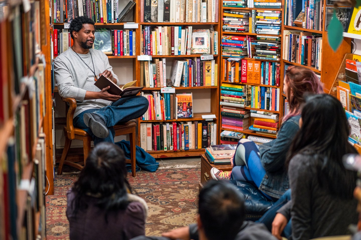 A man reads to a group of people in a bookstore