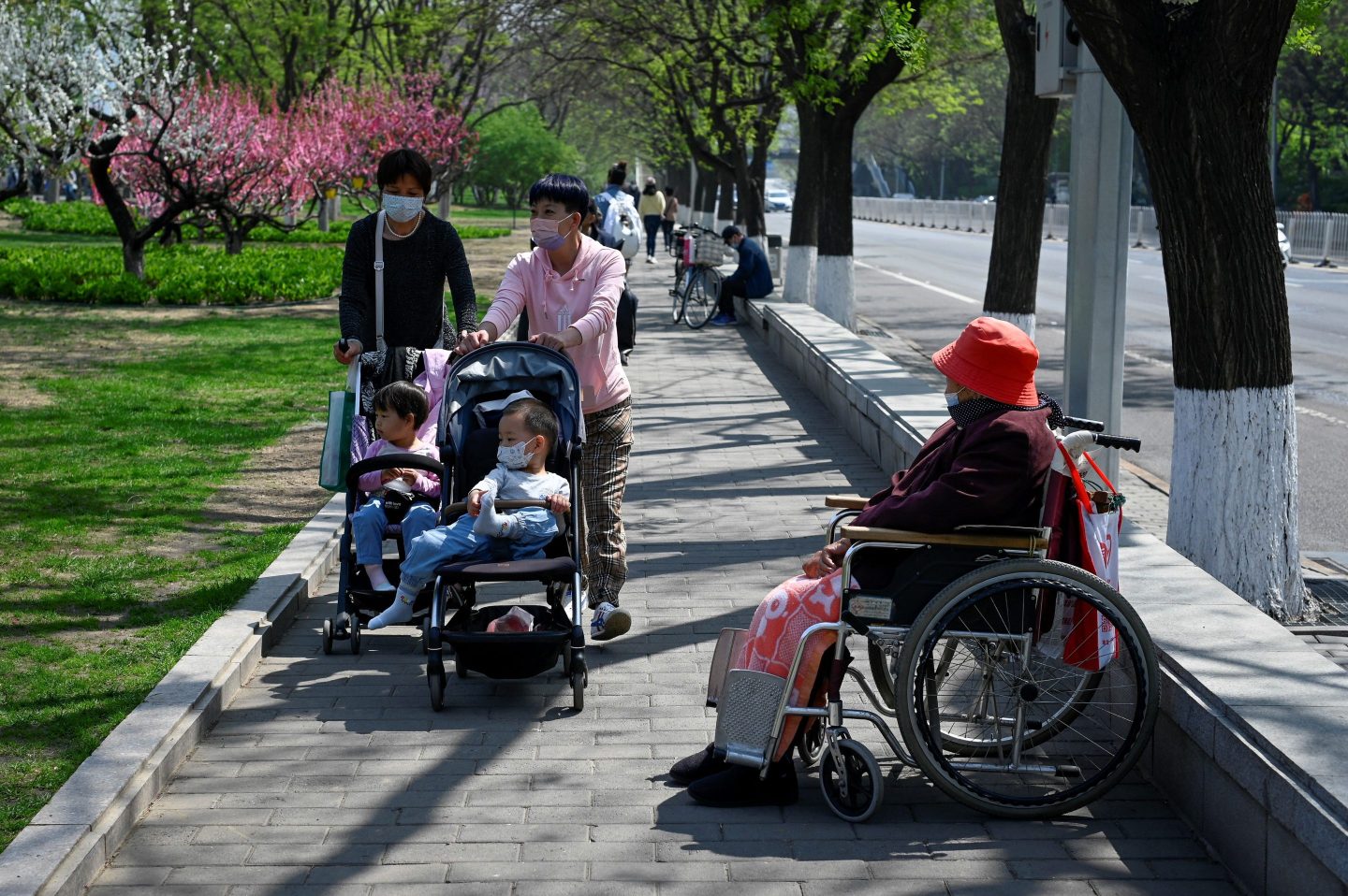 A Chinese family pushes a baby stroller past an elderly woman