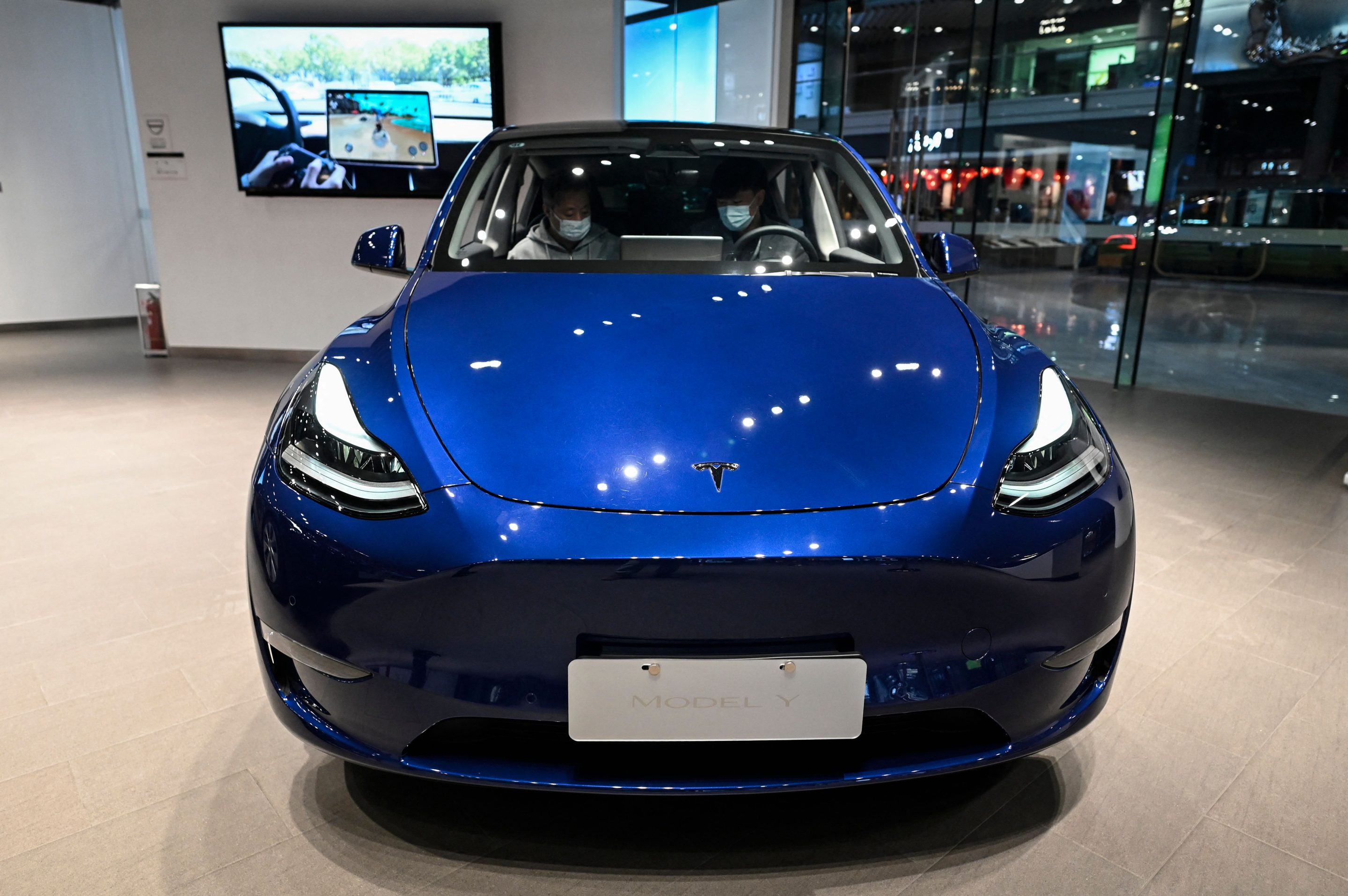 People try a Tesla Model Y car at a Tesla showroom at a shopping mall in Beijing on April 29.