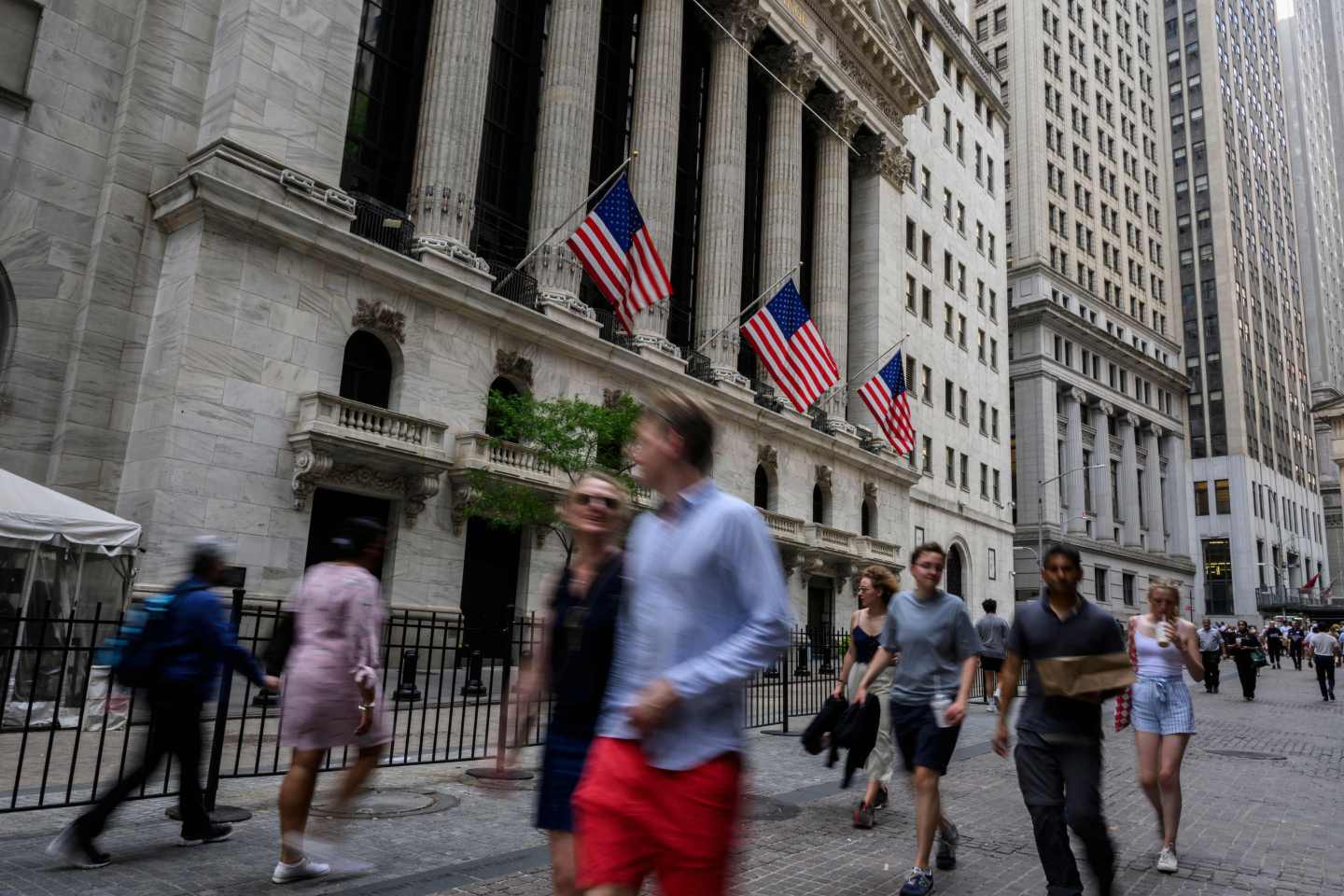People walk past the New York Stock Exchange (NYSE) on Wall Street.