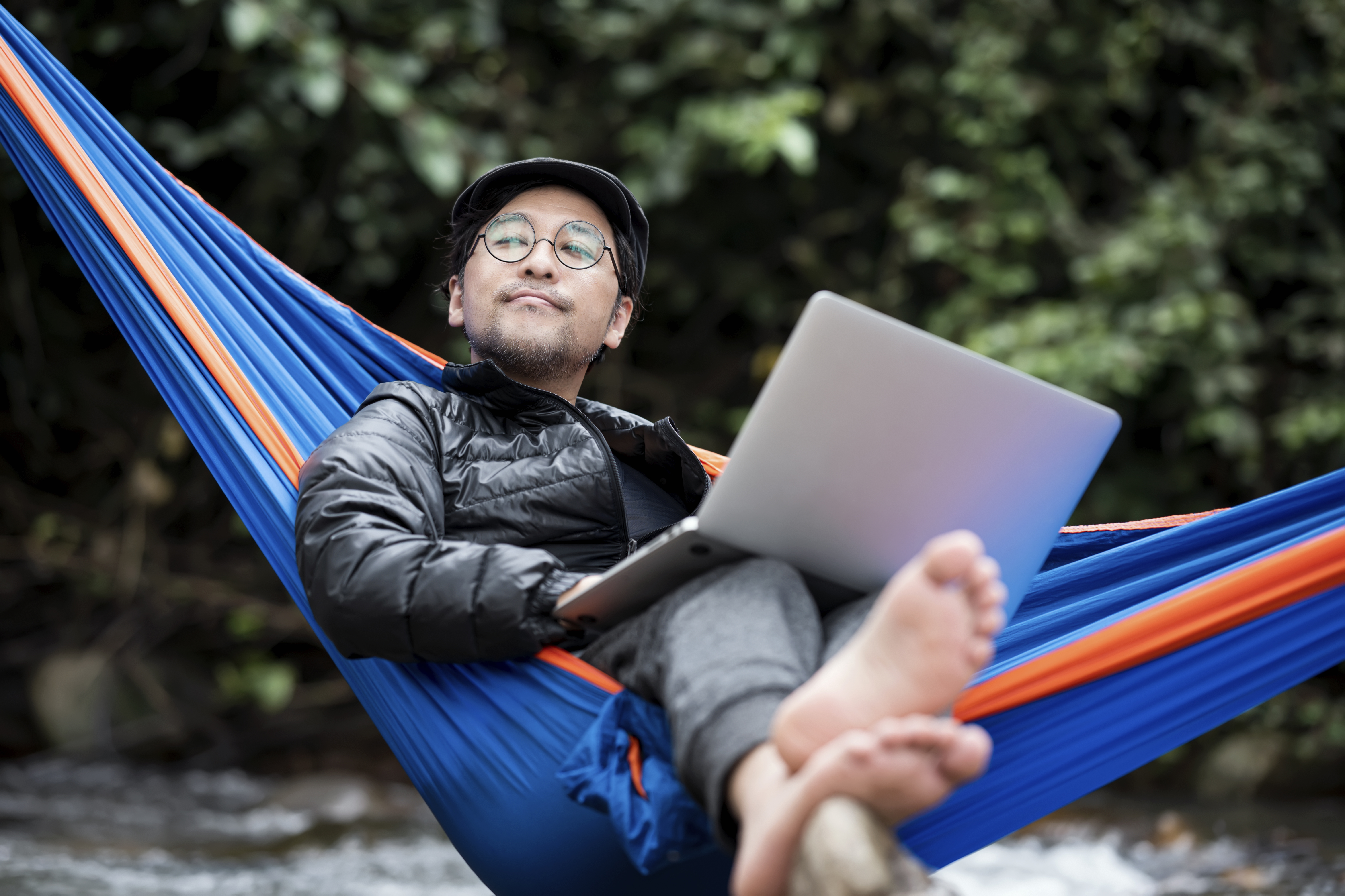 Man relaxing in hammock with laptop