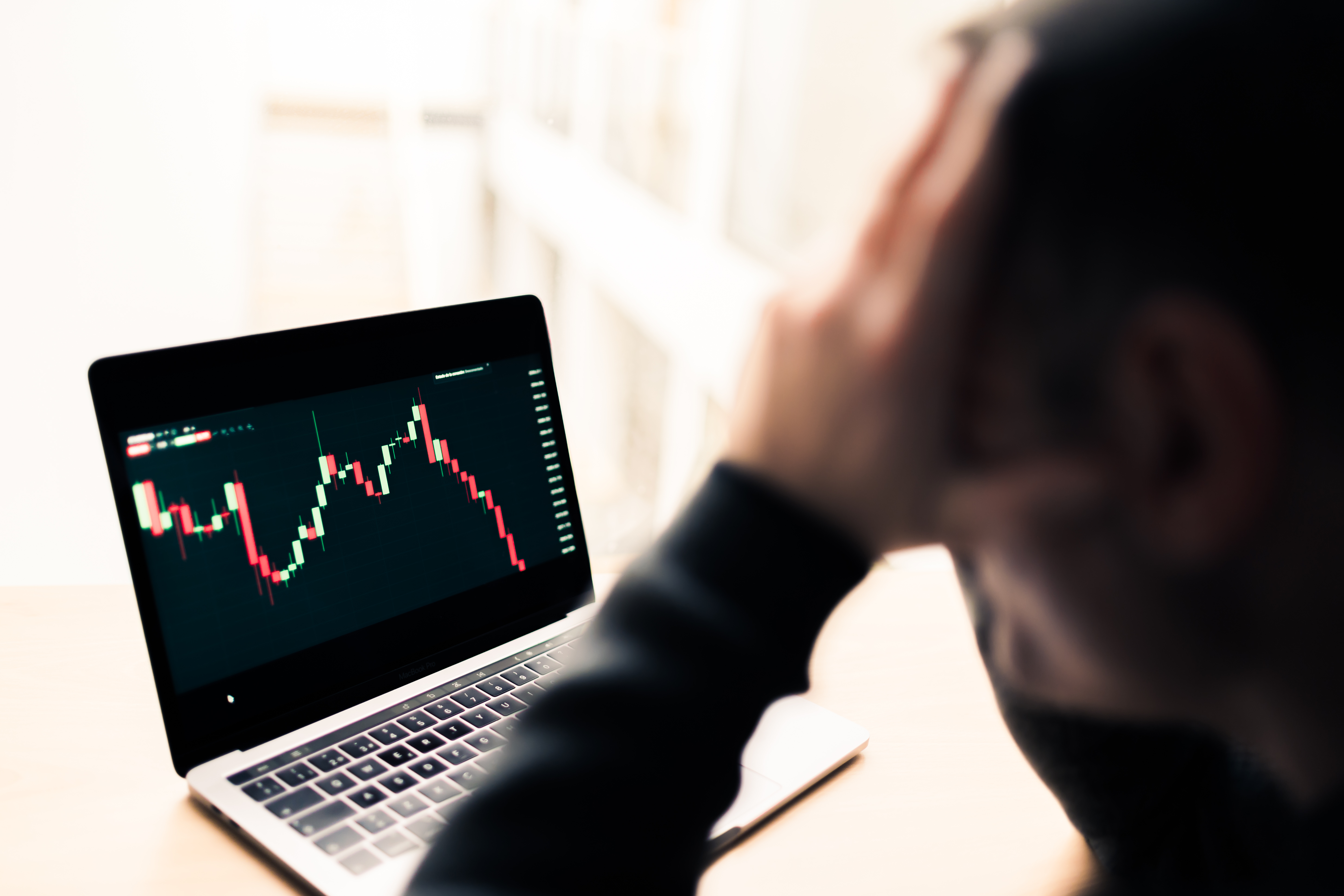 Pensive and sad man watching in his office the crash of the graph through the laptop