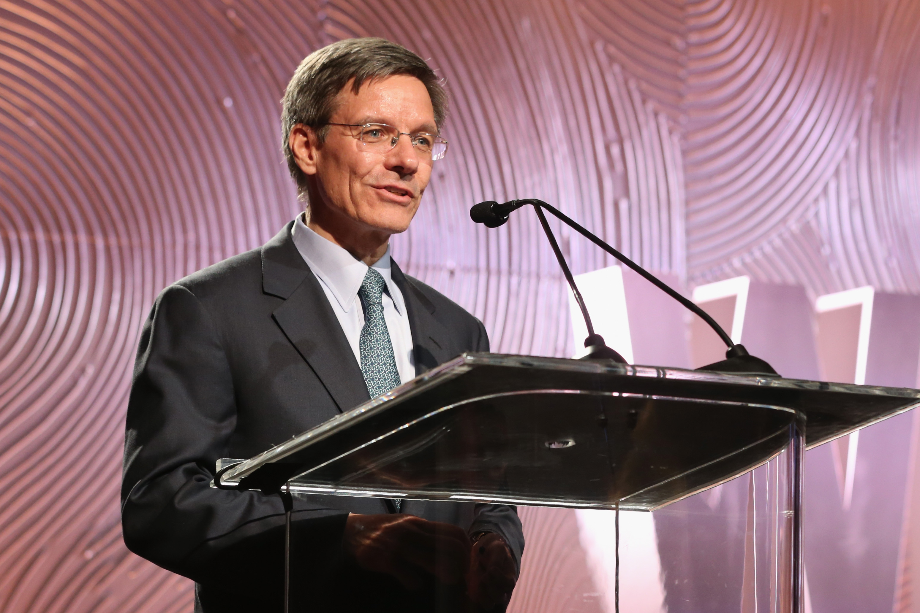 Allstate CEO Tom Wilson speaking at a podium.