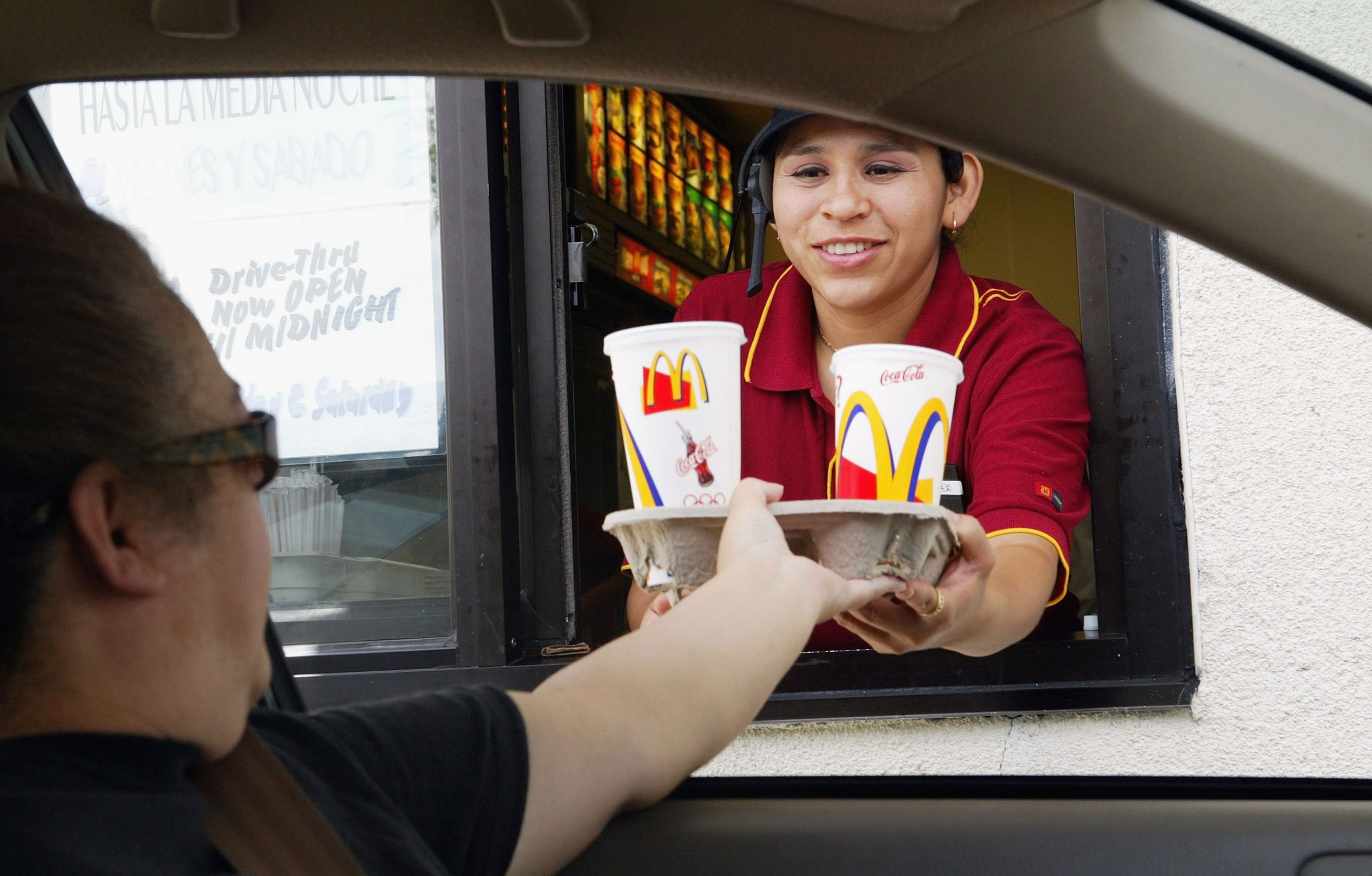 A McDonald's worker hands a meal to a drive-thru customer.