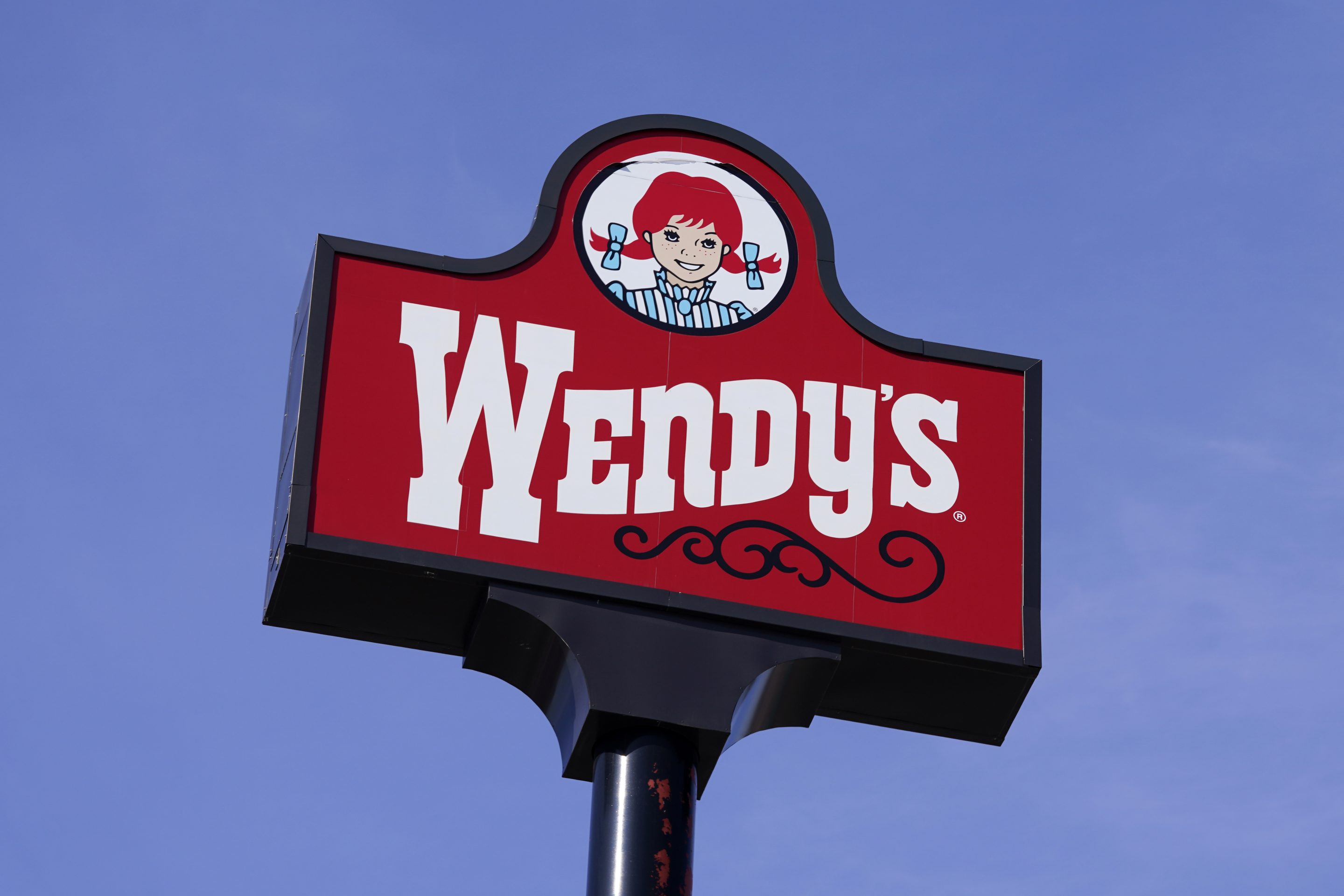 This Feb. 25, 2021, photo shows a sign over a Wendy's restaurant in Des Moines, Iowa. Wendy’s has announced, Friday, Aug. 19 that it’s pulling lettuce from sandwiches in stores in Michigan, Ohio and Pennsylvania after people eating sandwiches there reported falling ill. The Centers for Disease Control and Prevention is investigating the source of the illness.