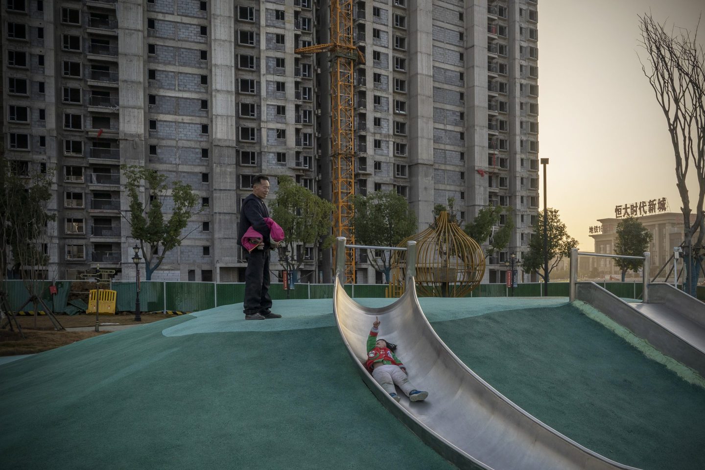 A child on a slide in front of unfinished apartment buildings in Wuhan, China.