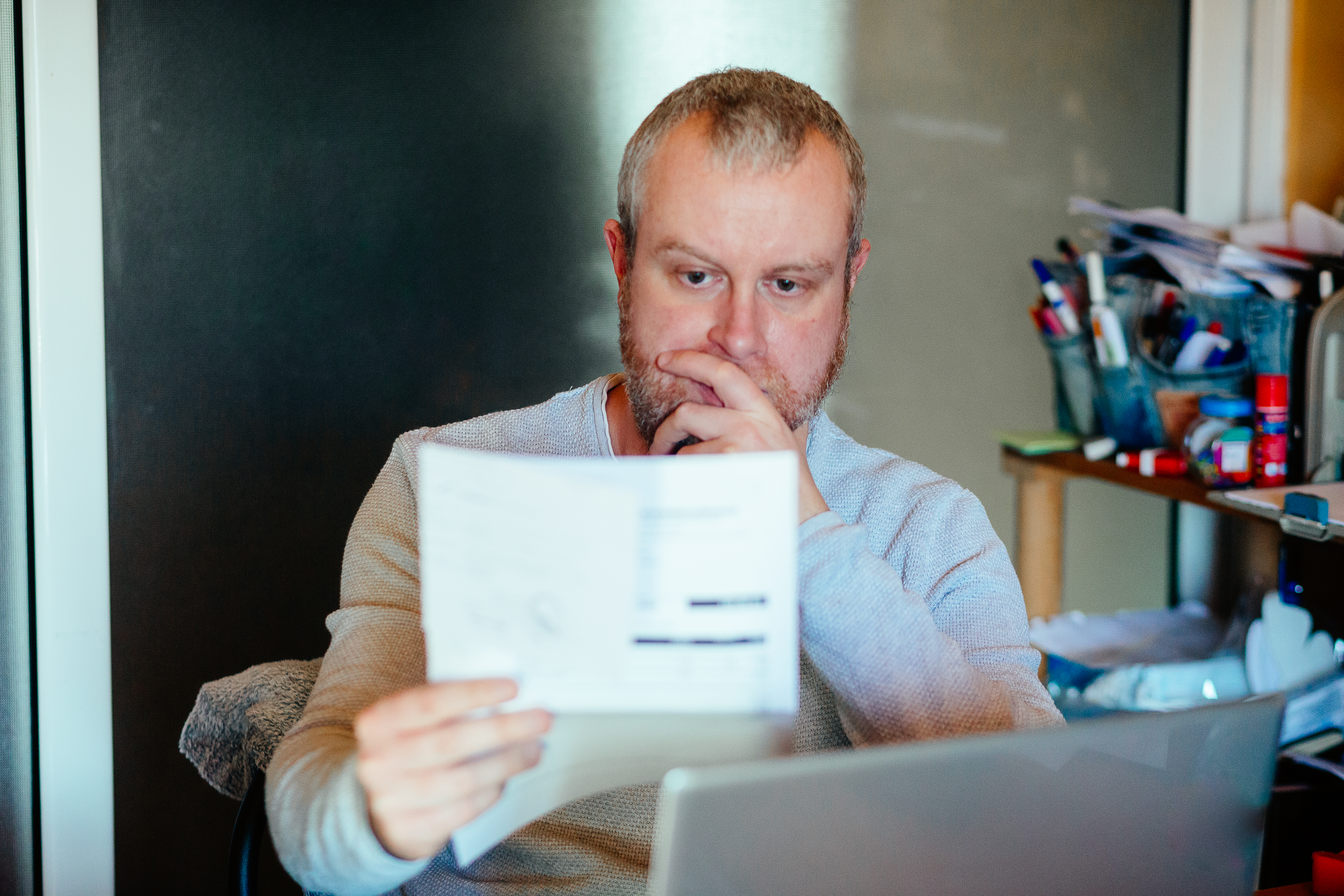 A man looking worried as he looks at a bill.