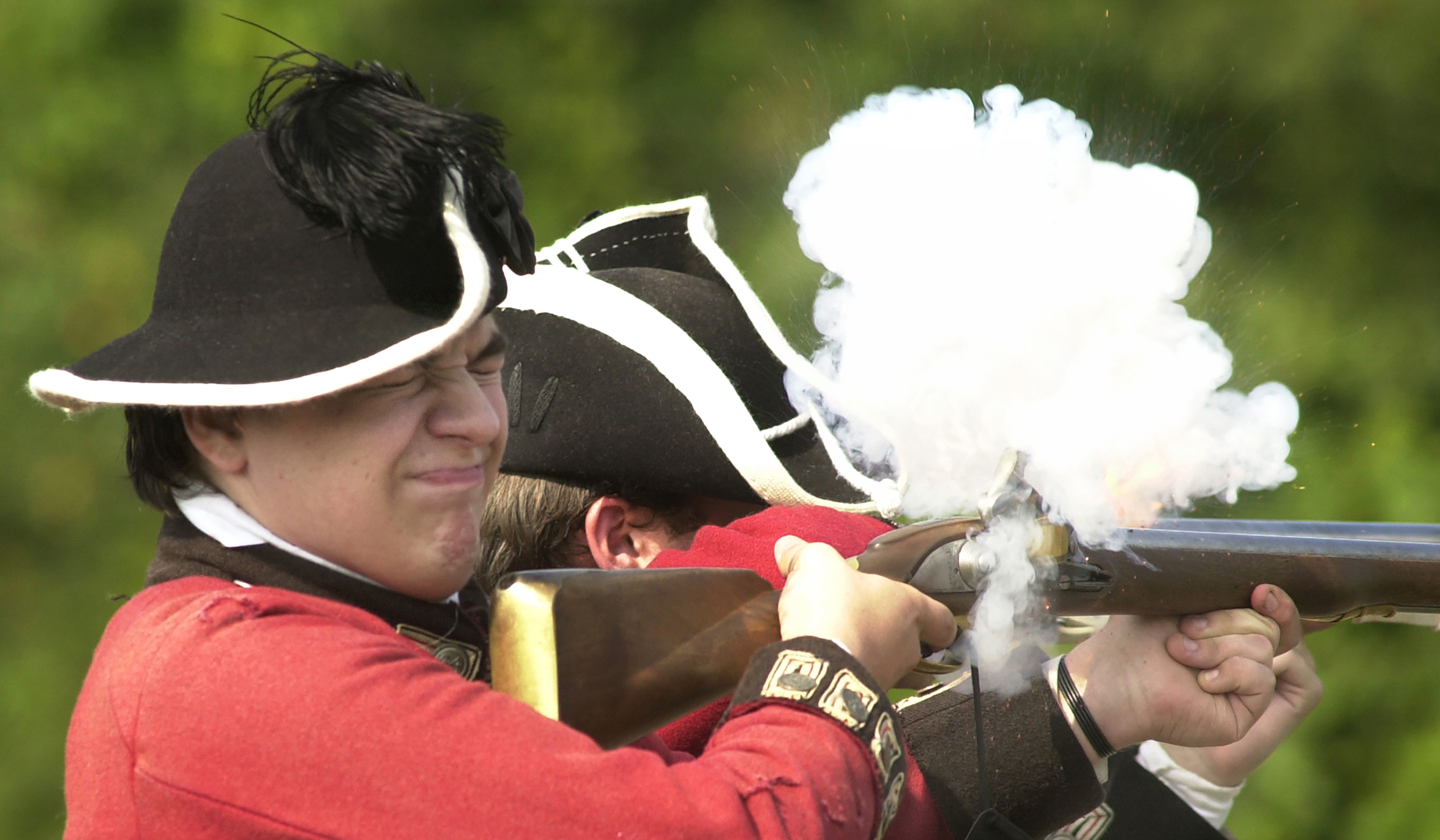 Private soldier Chance Jones of Manhattan, and a first-time Revolutionary War re-enactor, squints as he fires 90-grain black powder at advancing American re-enactors during the 225th anniversary reenactment of the Battle of Newtown, Aug. 28, 2004, in Lowman, N.Y.