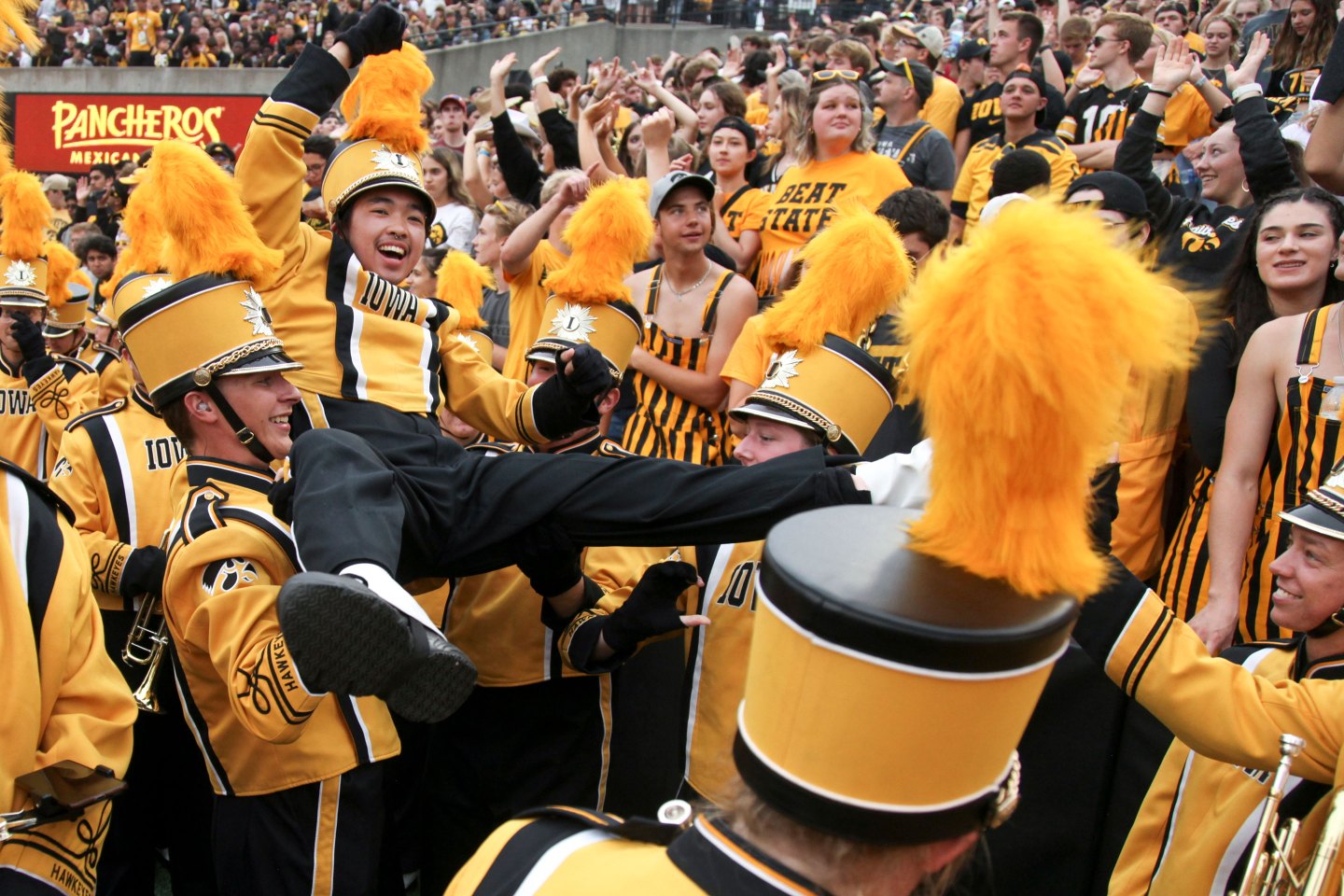 Members of the Iowa Marching Band celebrate with fans in the student section during a September 2022 game at Kinnick Stadium.