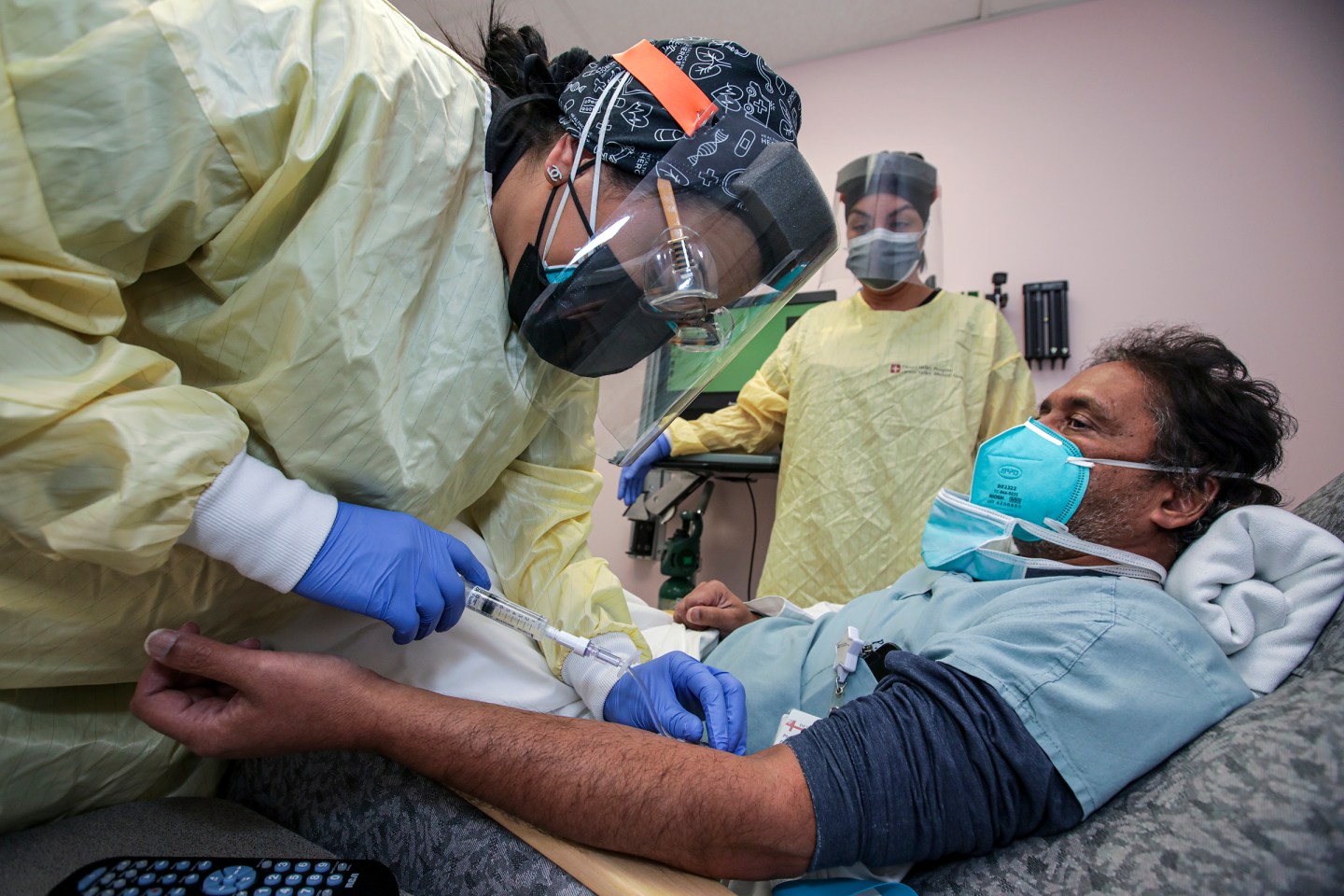 Nurse Salina Padilla, left, prepares Dr. Prabakar Tummala for a monoclonal antibody infusion at Desert Valley Hospital on Dec. 17, 2020 in Victorville, CA.