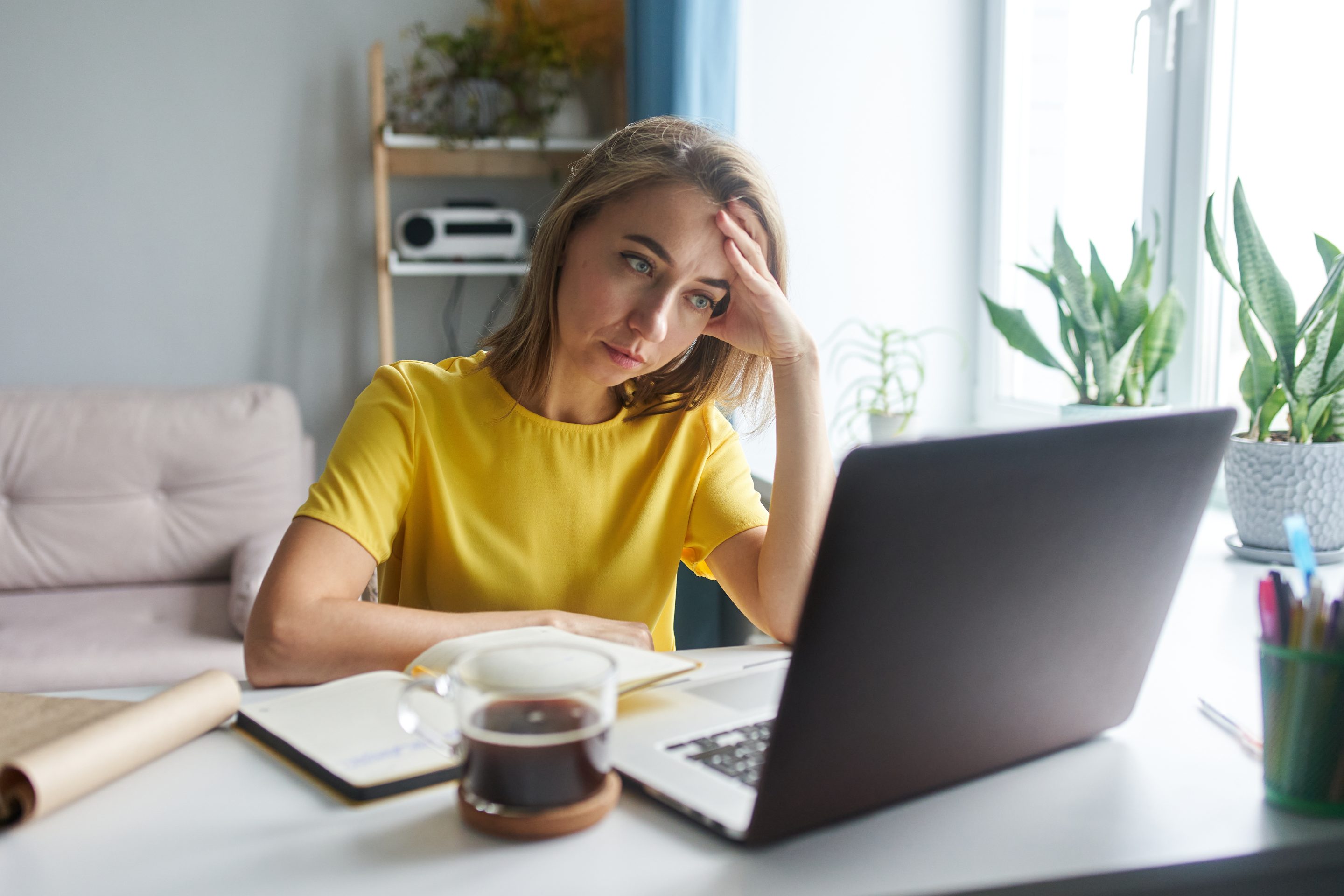 A woman sits in front of a laptop in emotional tension