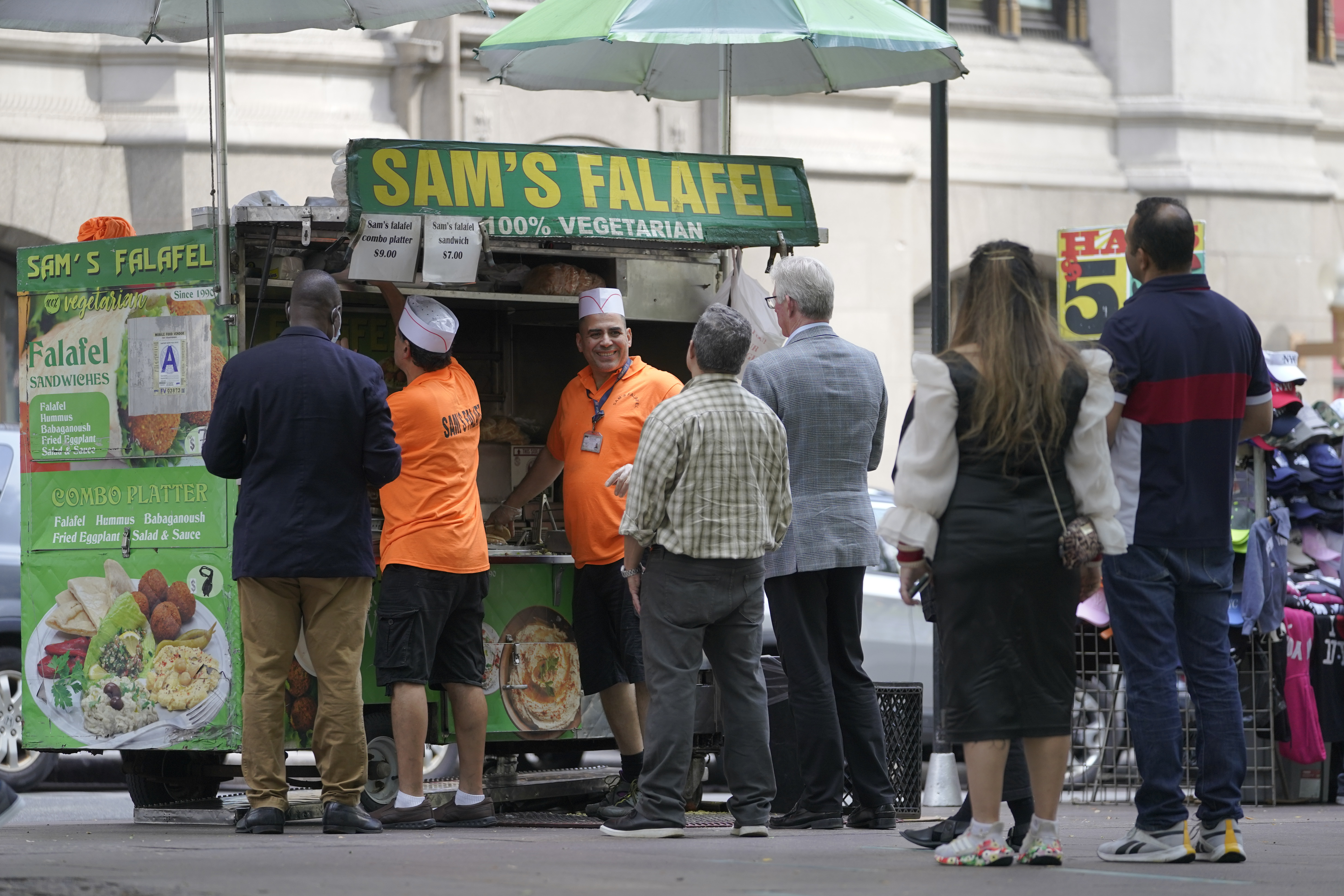 Emad Ahmed, center facing camera, works at his falafel cart in Zuccotti park in the financial district of New York,  Sept. 13, 2022. 