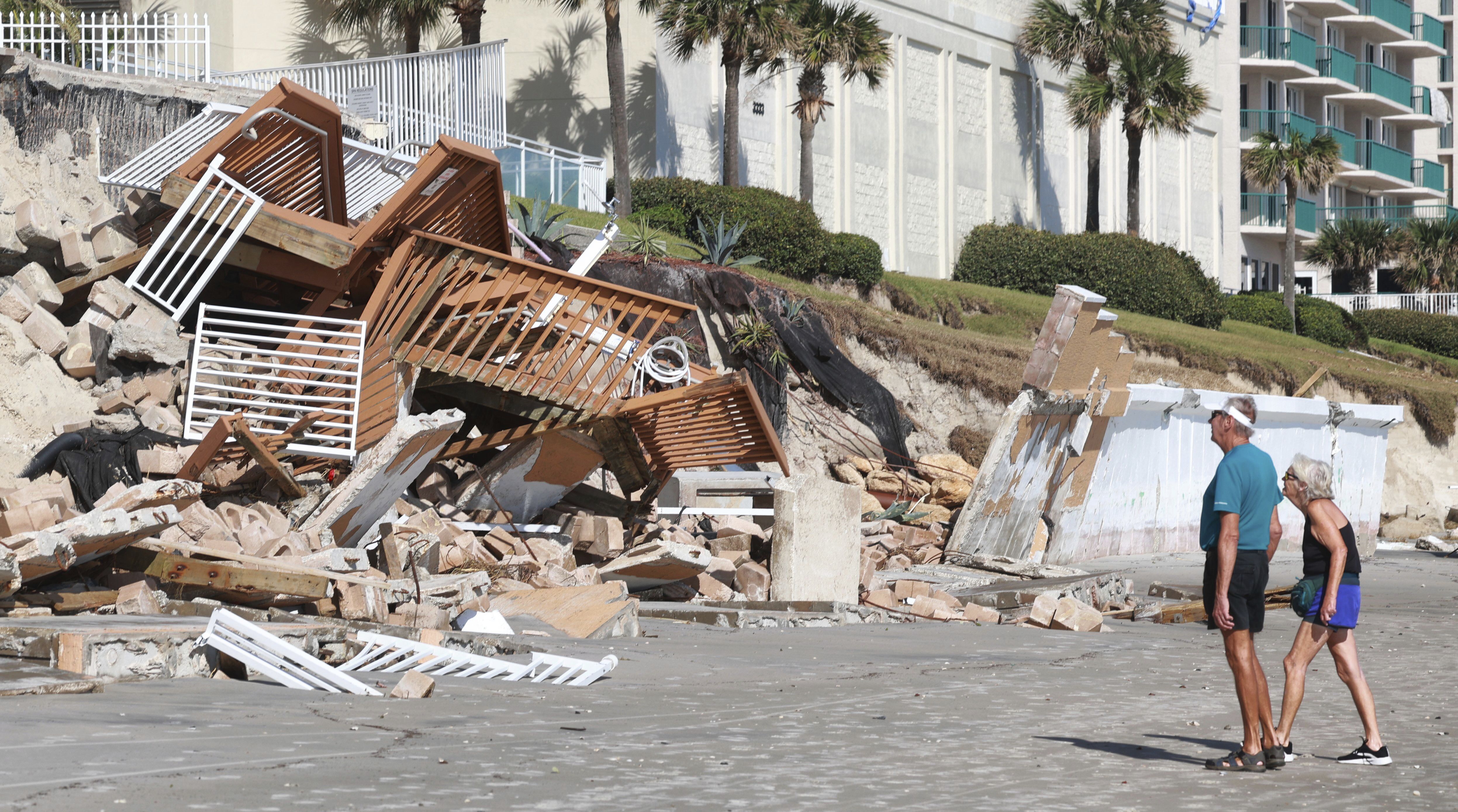 Beachgoers survey the damage on Oct. 3, 2022, in Daytona Beach Shores, Fla.