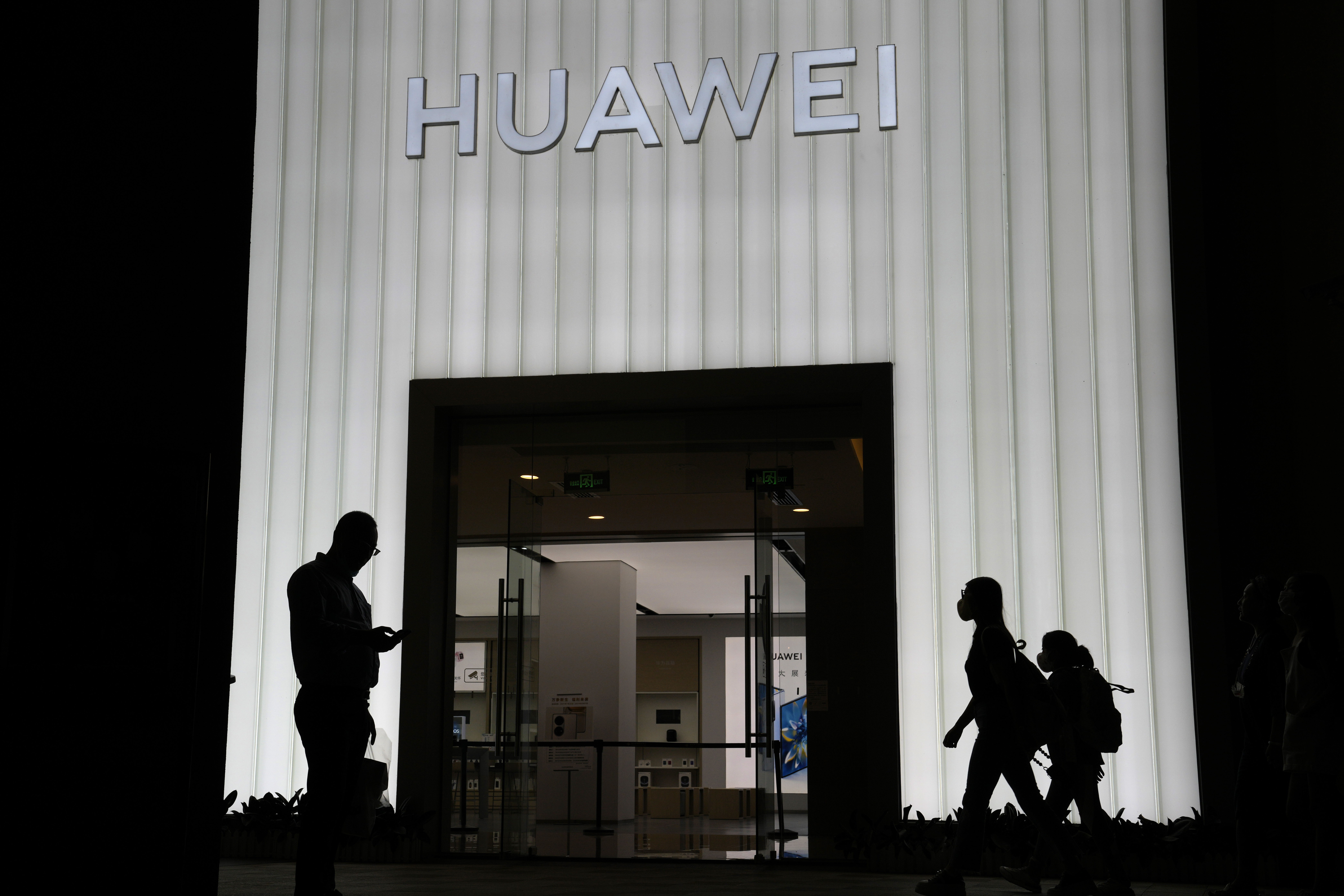 Shoppers pass by a Huawei store in Beijing, China