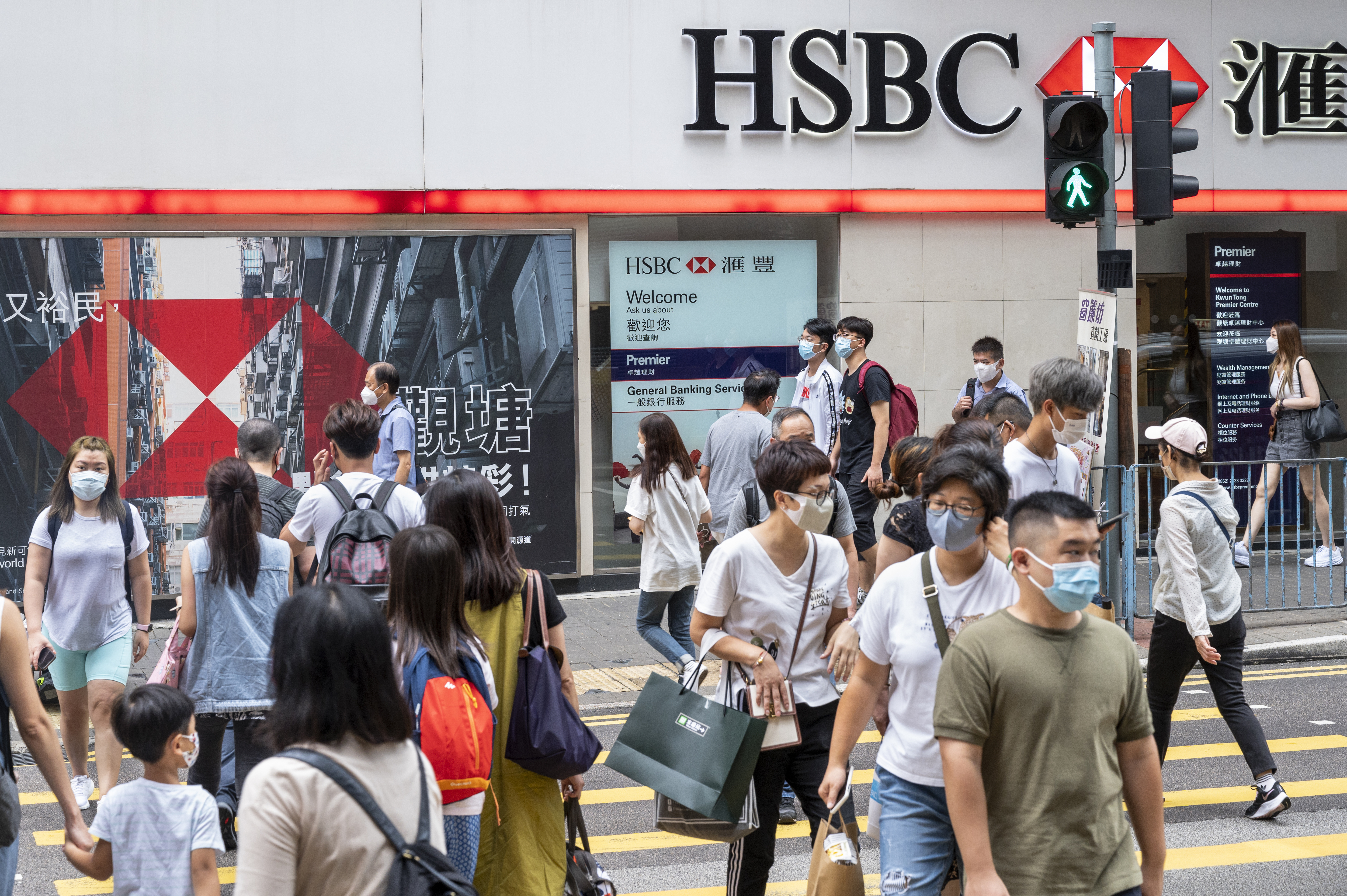 Pedestrians cross the street in front of HSBC Bank in Hong Kong. 