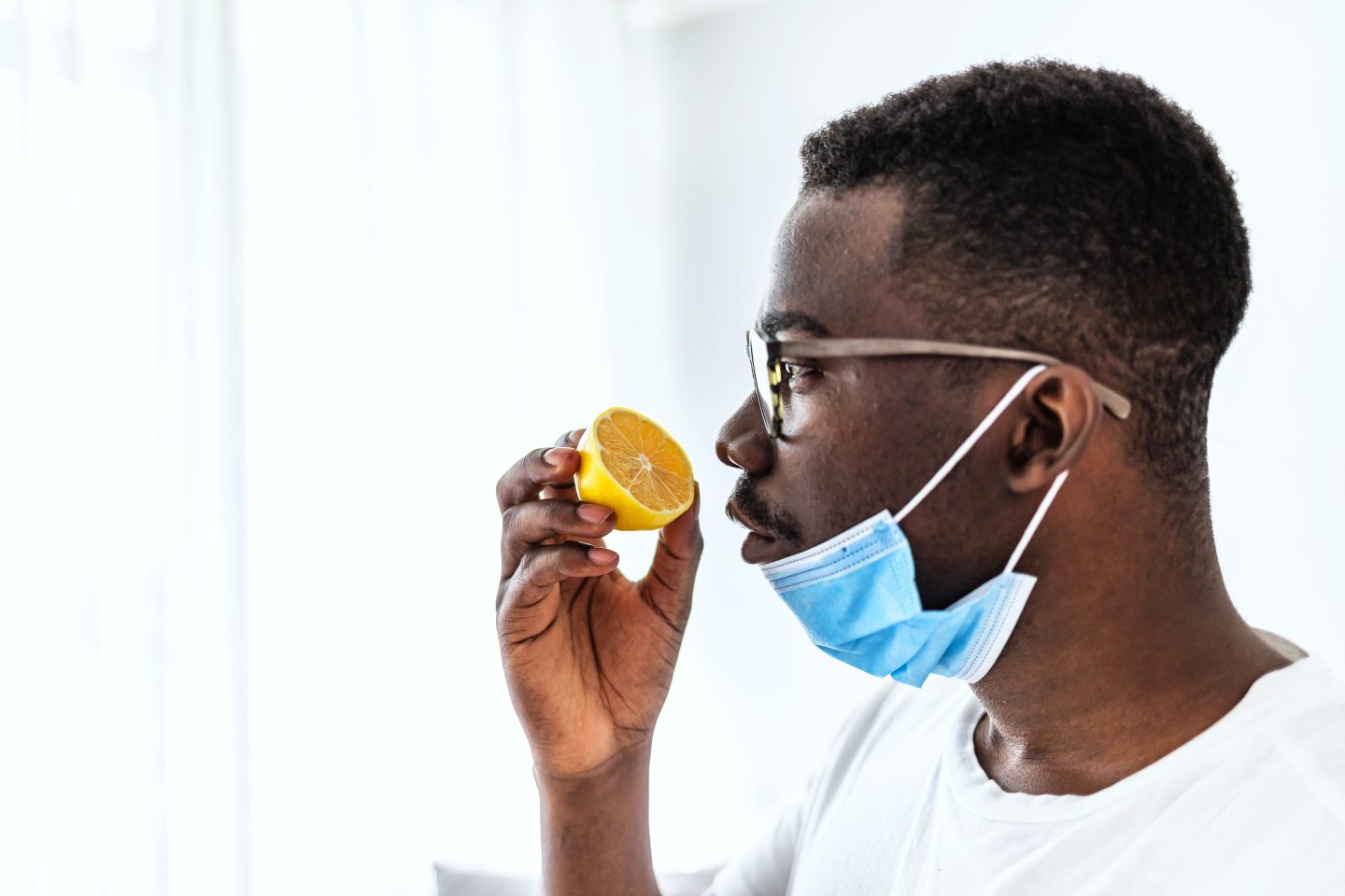 man Trying to Sense Smell of a Lemon at home during the day,