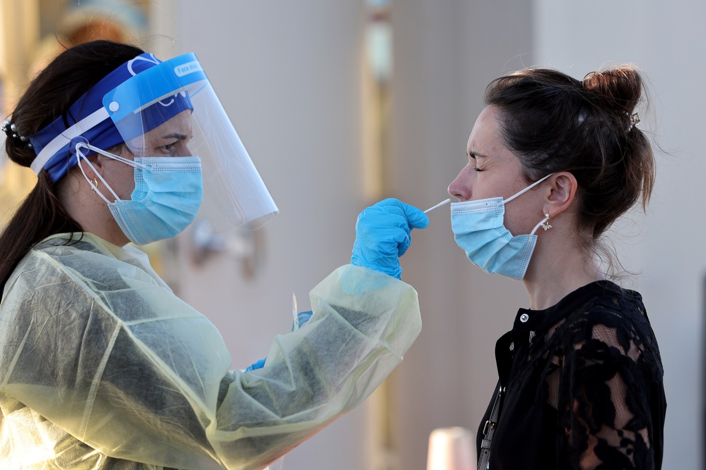 A medical worker giving a woman a COVID nasal swab.