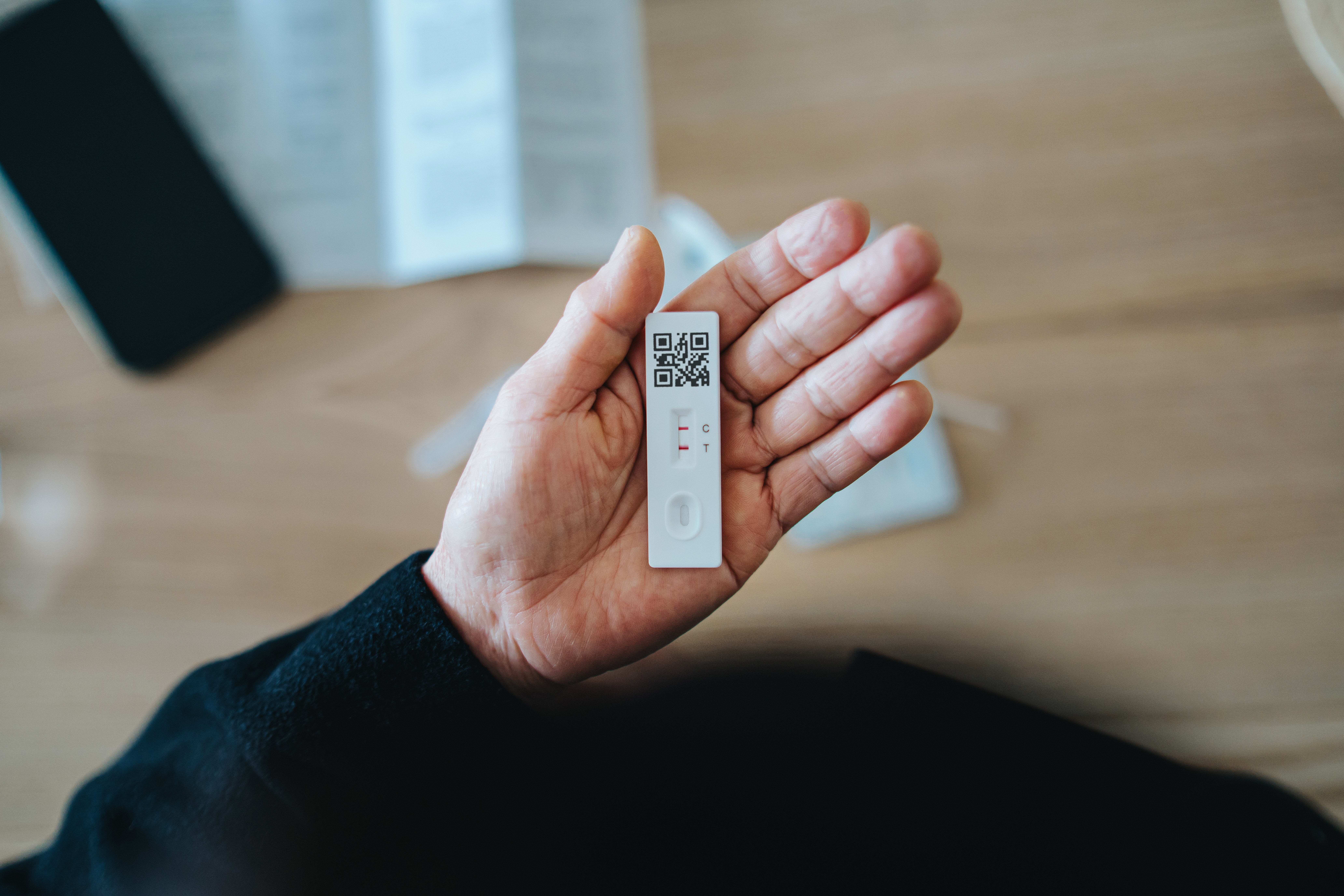 A woman holds a COVID-19 rapid self test device, which displays a positive result.