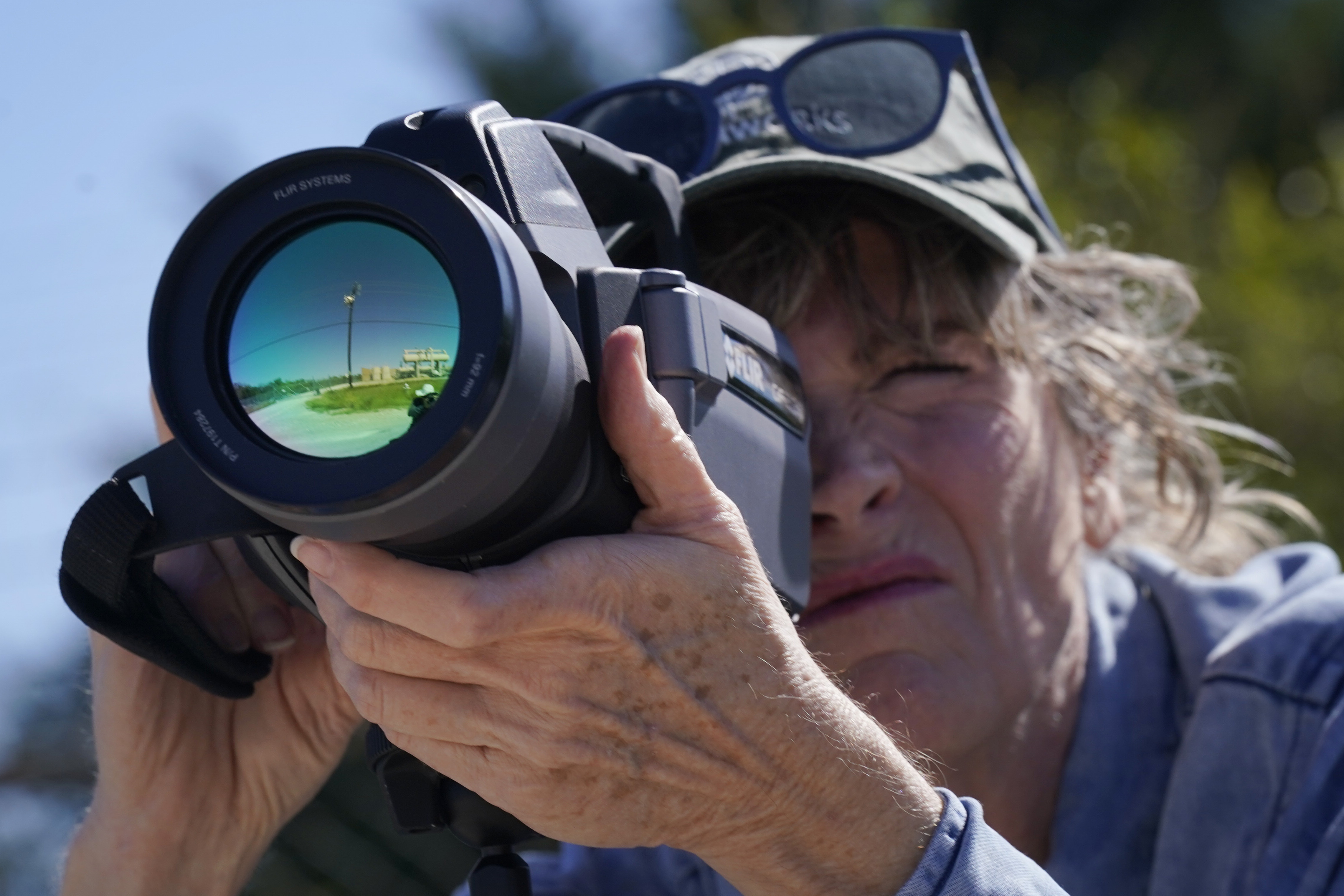 Sharon Wilson points a thermal imaging camera towards a compressor station in Arlington, Texas, Oct. 18, 2022.