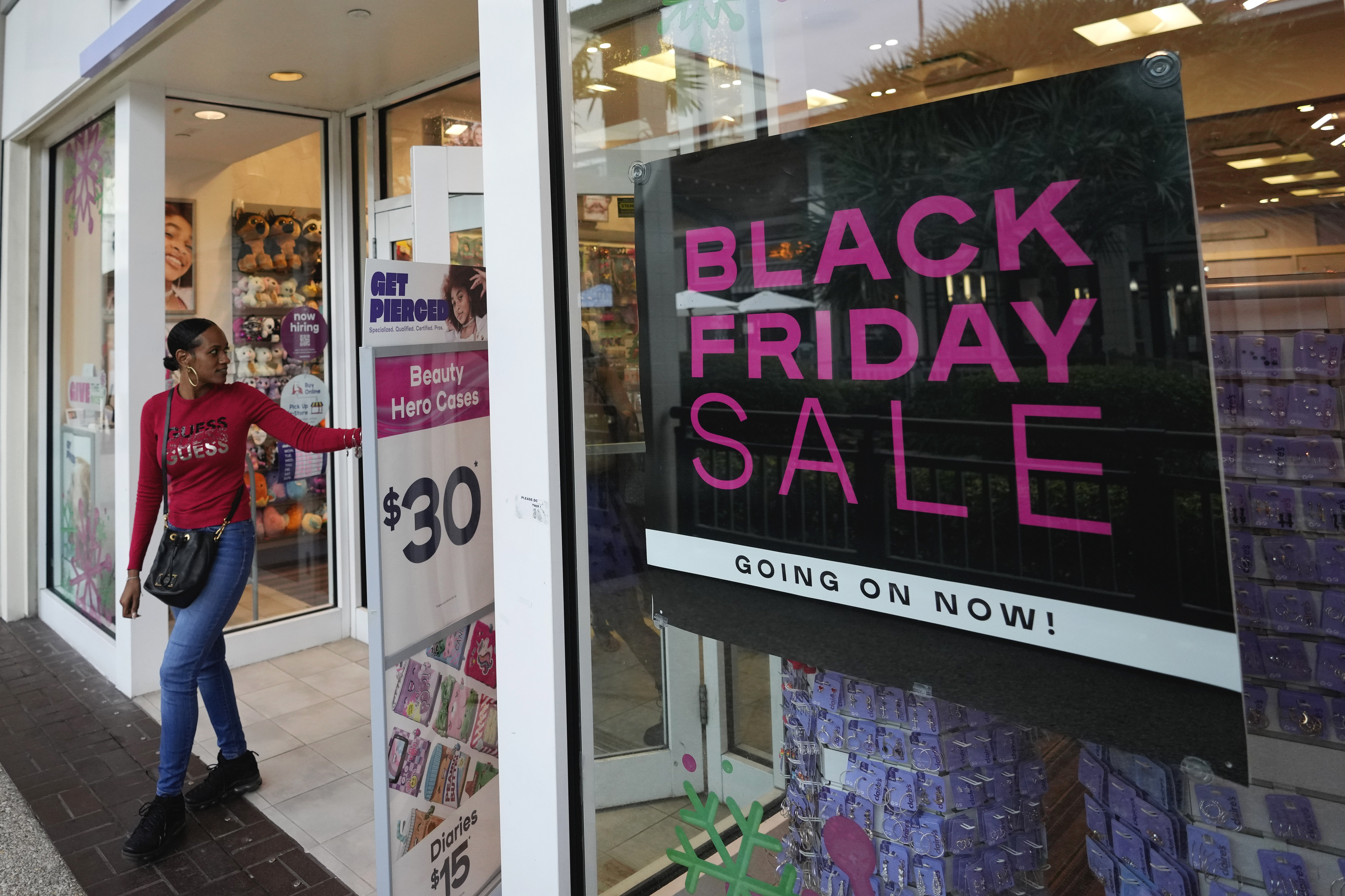 Shoppers exit a Claire's accessories store advertising sales ahead of Black Friday and the Thanksgiving holiday, Nov. 21, 2022, in Miami. Retailers are ushering in the start of the holiday shopping season on the day after Thanksgiving, preparing for the biggest crowds since 2019. 