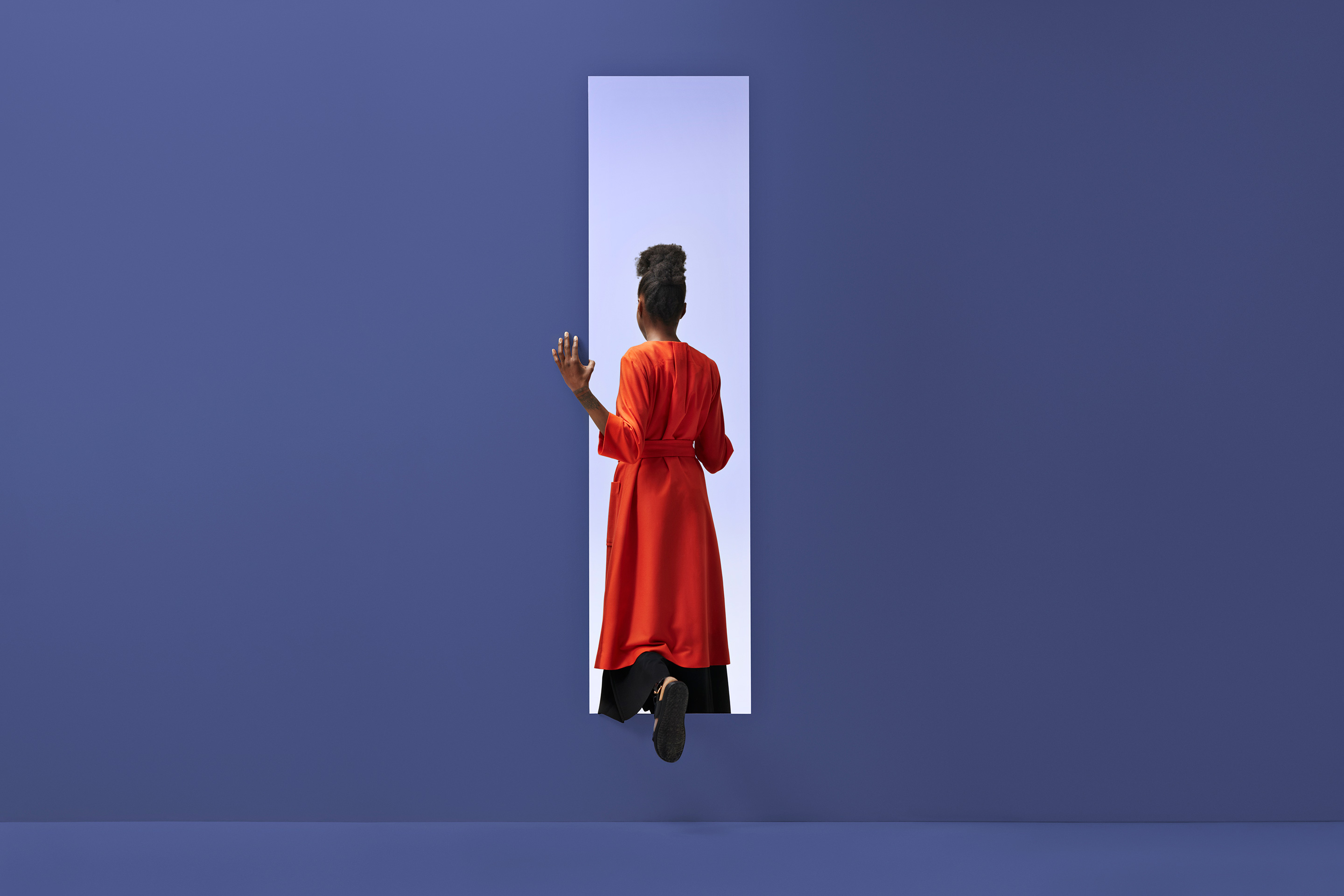 Black womam walking through a door in purple.
