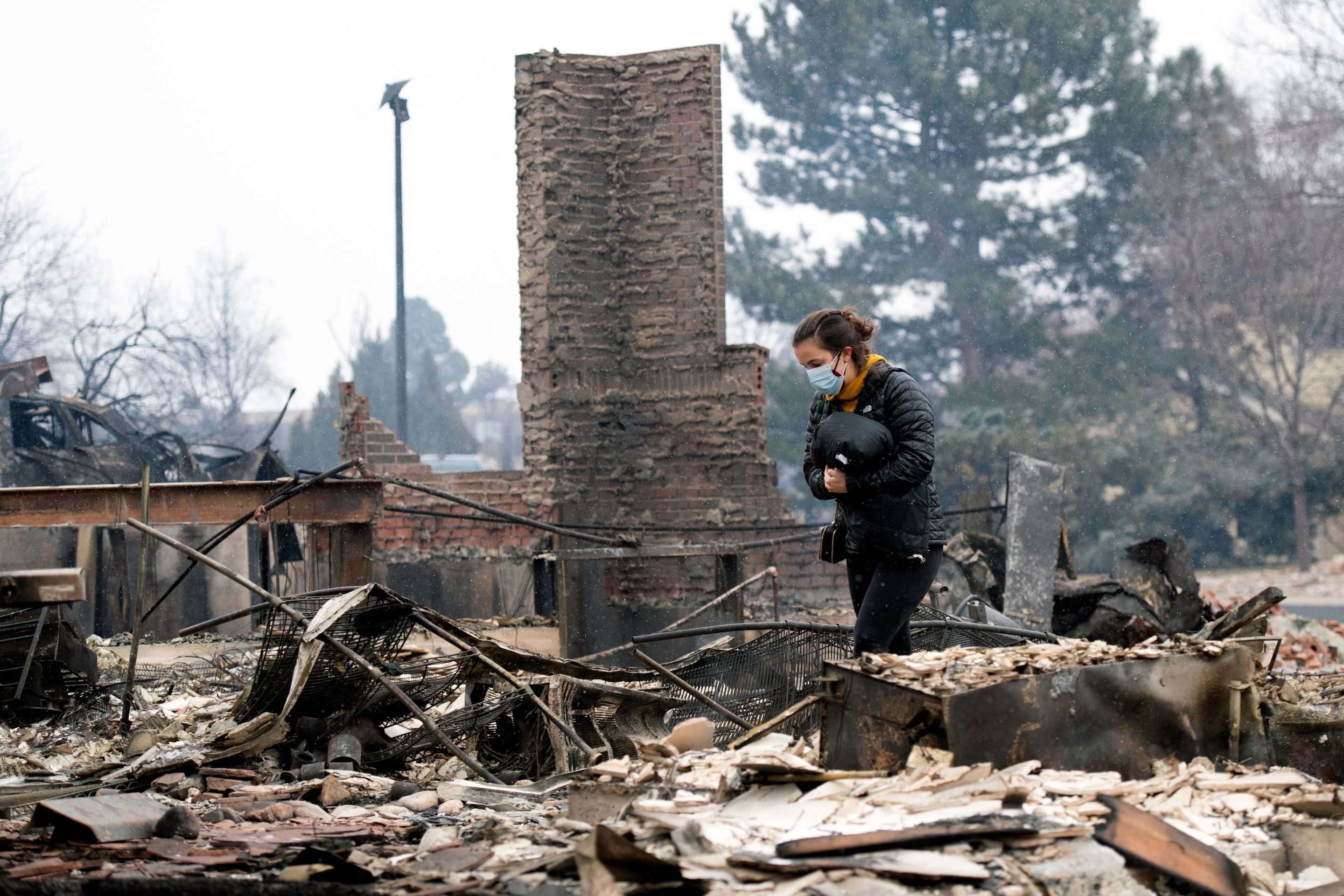 A resident of Louisville, Colo., walks through the remains of her childhood home on Dec. 31, 2021. A fast-spreading wildfire tore through several Colorado towns before burning itself out.