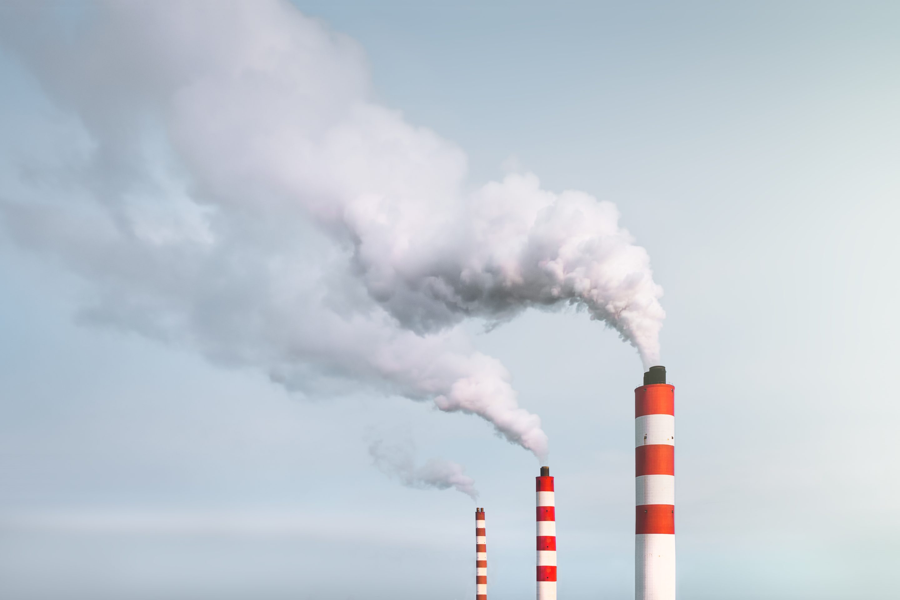 White smoke is pouring out of the chimneys of the power plant.
