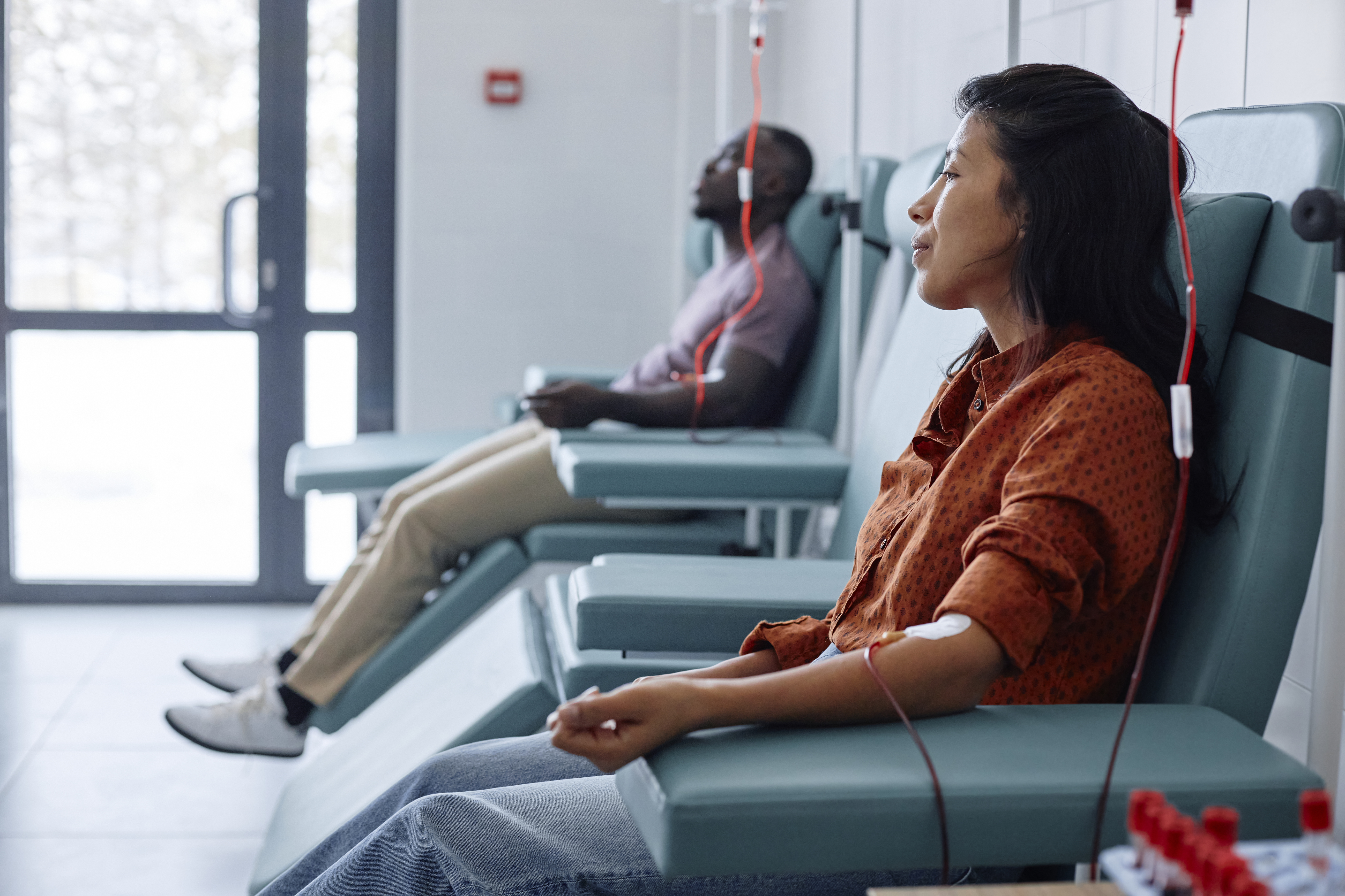 A man and a woman are seen donating blood in a hospital