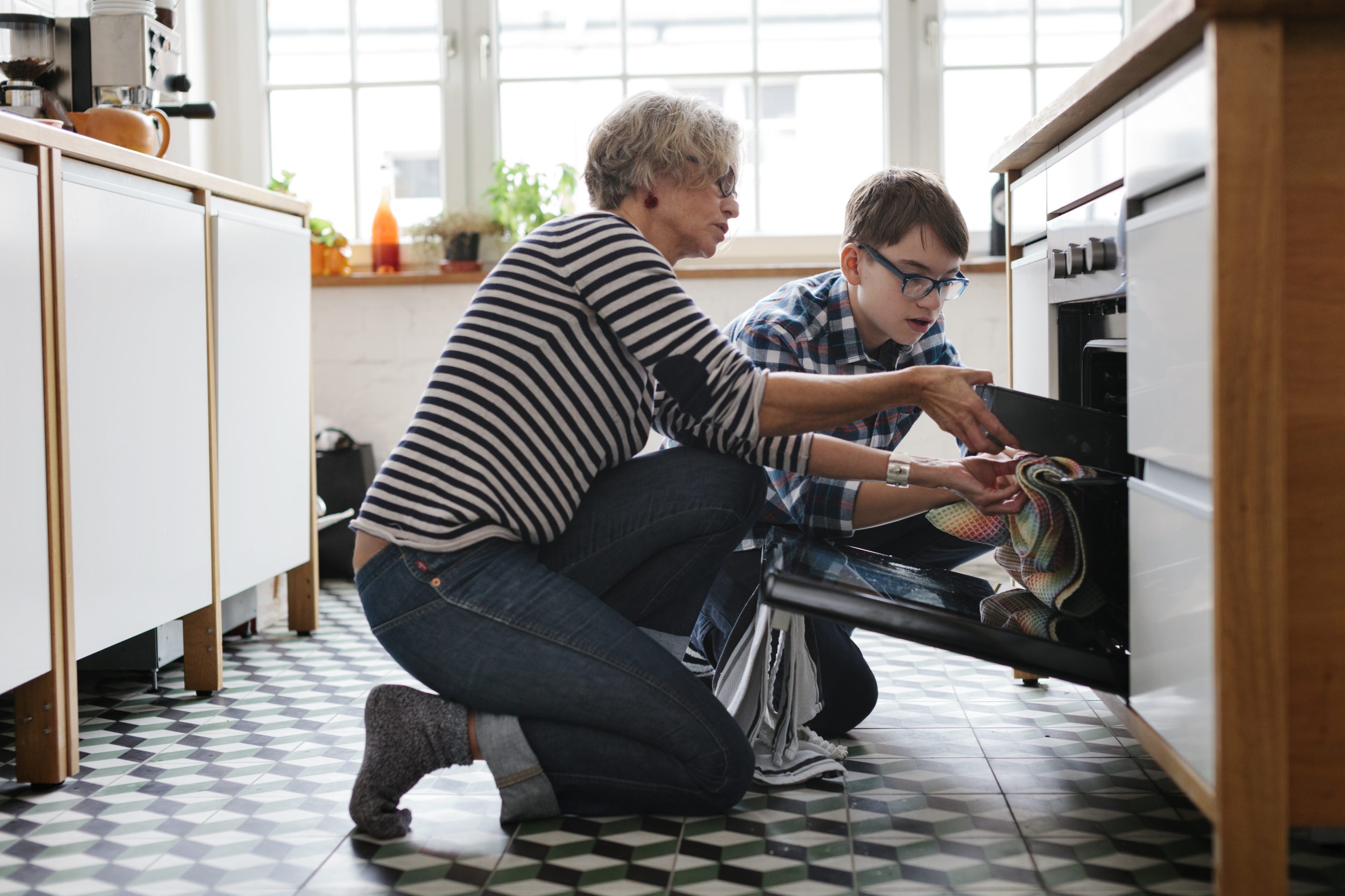 Mature Mother teaching her teenage Son how to bake