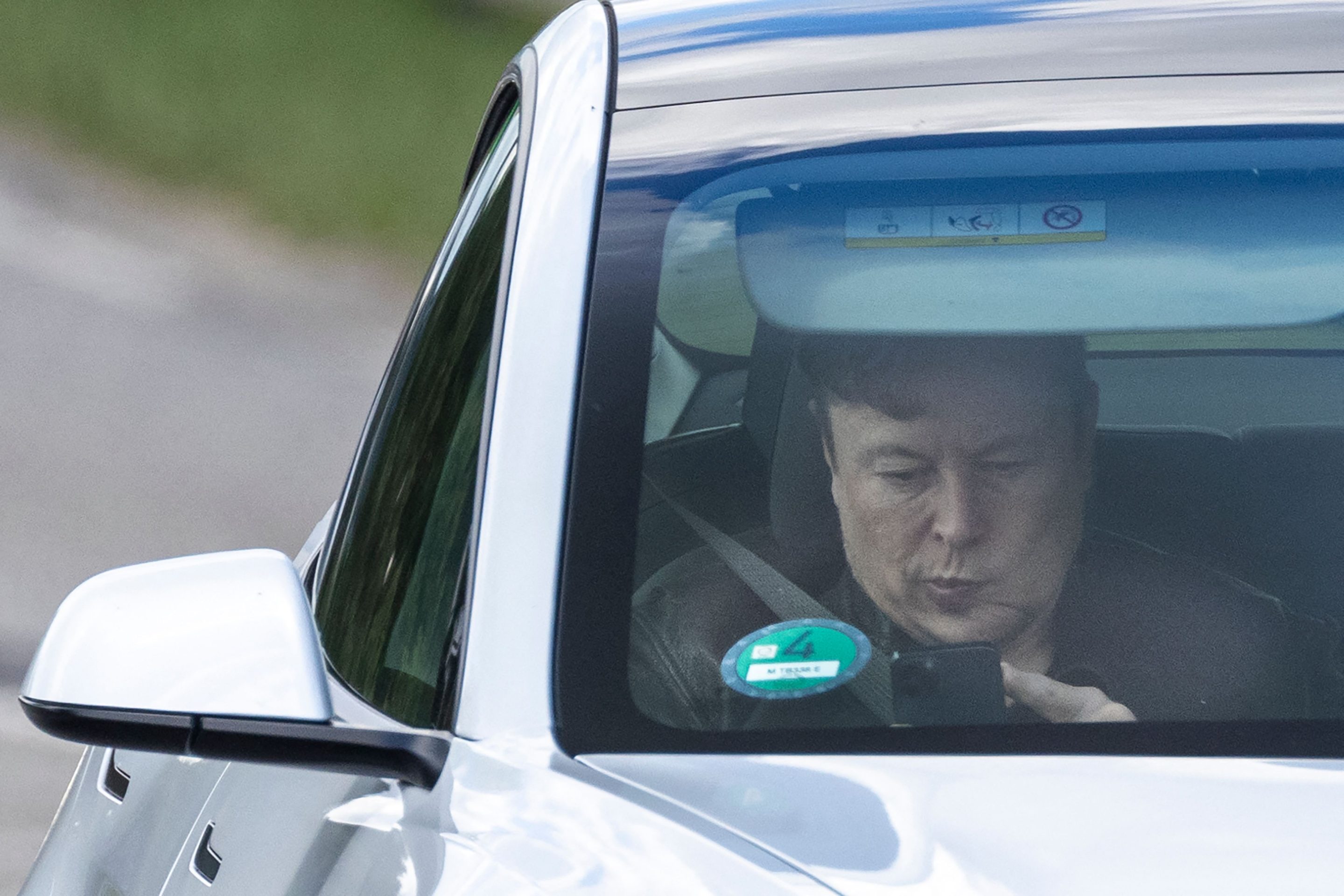 Tesla CEO Elon Musk uses his mobile device as he sits in the car arriving to the construction site for the new plant, the so-called "Giga Factory", of US electric carmaker Tesla in Gruenheide near Berlin, northeastern Germany.