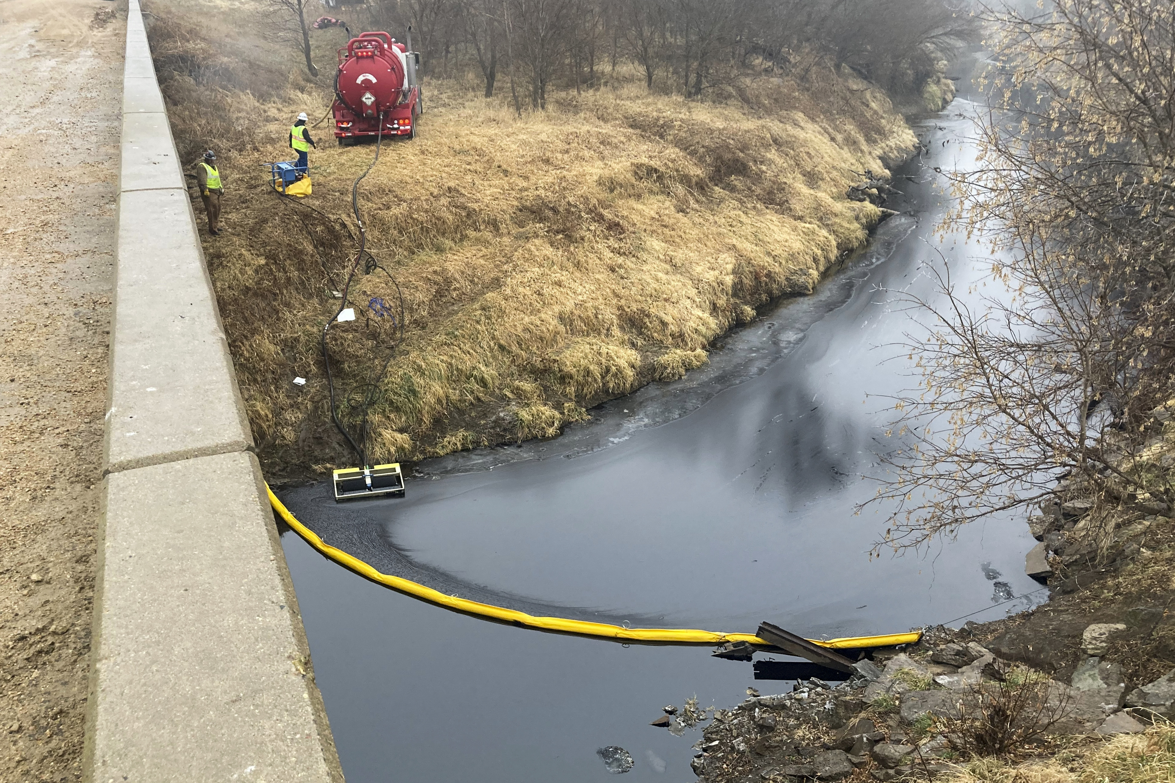 A remediation company deploys a boom on the surface of an oil spill after a Keystone pipeline ruptured at Mill Creek in Washington County, Kansas, on Dec. 8, 2022. Vacuum trucks, booms and an emergency dam were constructed on the creek to intercept the spill.