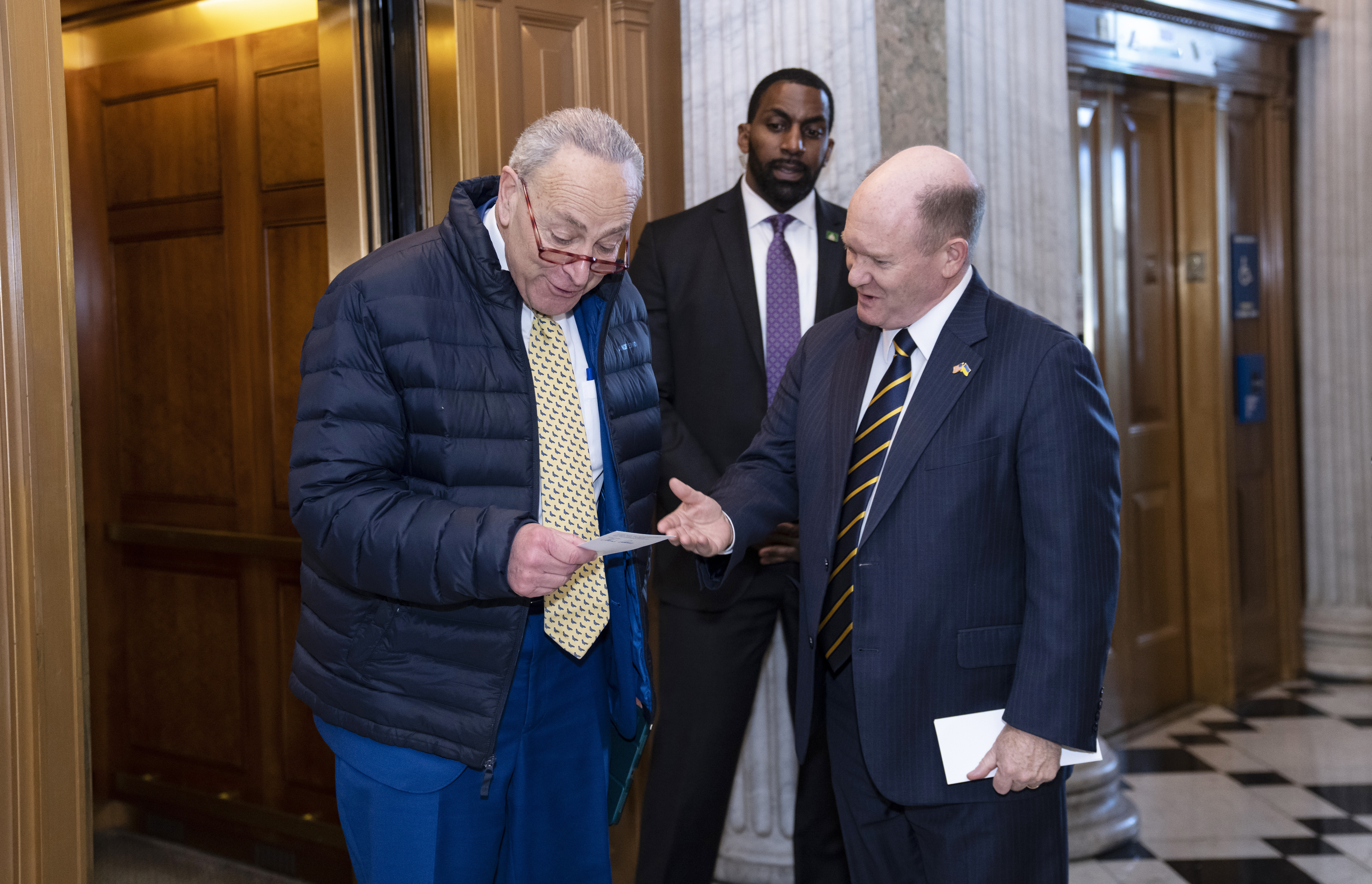 Senate Majority Leader Chuck Schumer, D-N.Y., left, confers with Sen. Chris Coons, D-Del., outside the chamber as lawmakers rush to complete passage of a $1.7 trillion bill to fund the government before a midnight Friday deadline or face the prospect of a partial government shutdown going into the Christmas holiday, at the Capitol in Washington, Dec. 21, 2022.