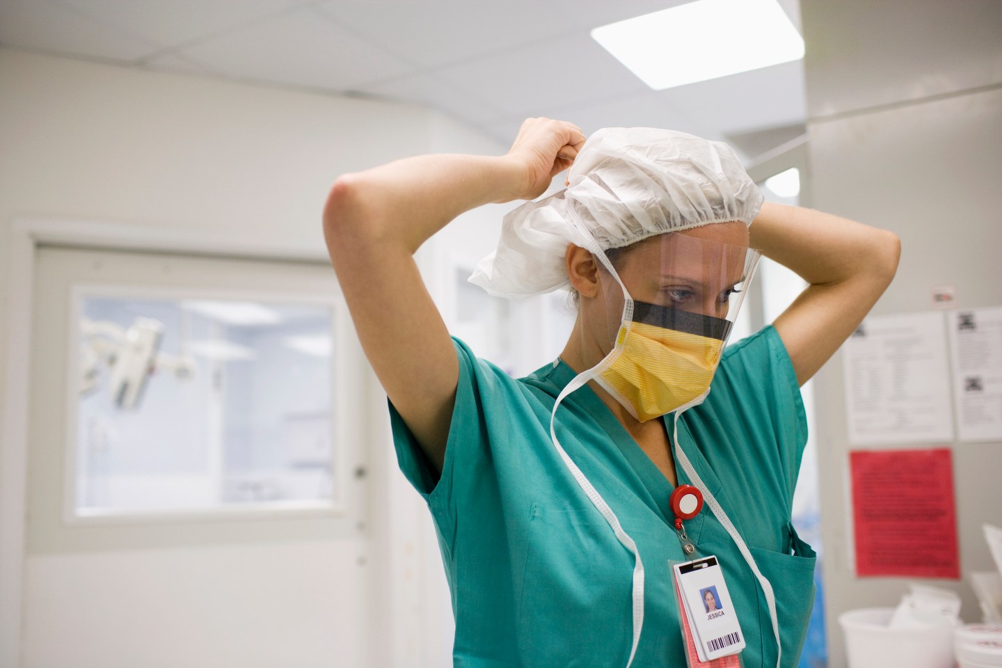 person in scrubs wearing mask and face shield