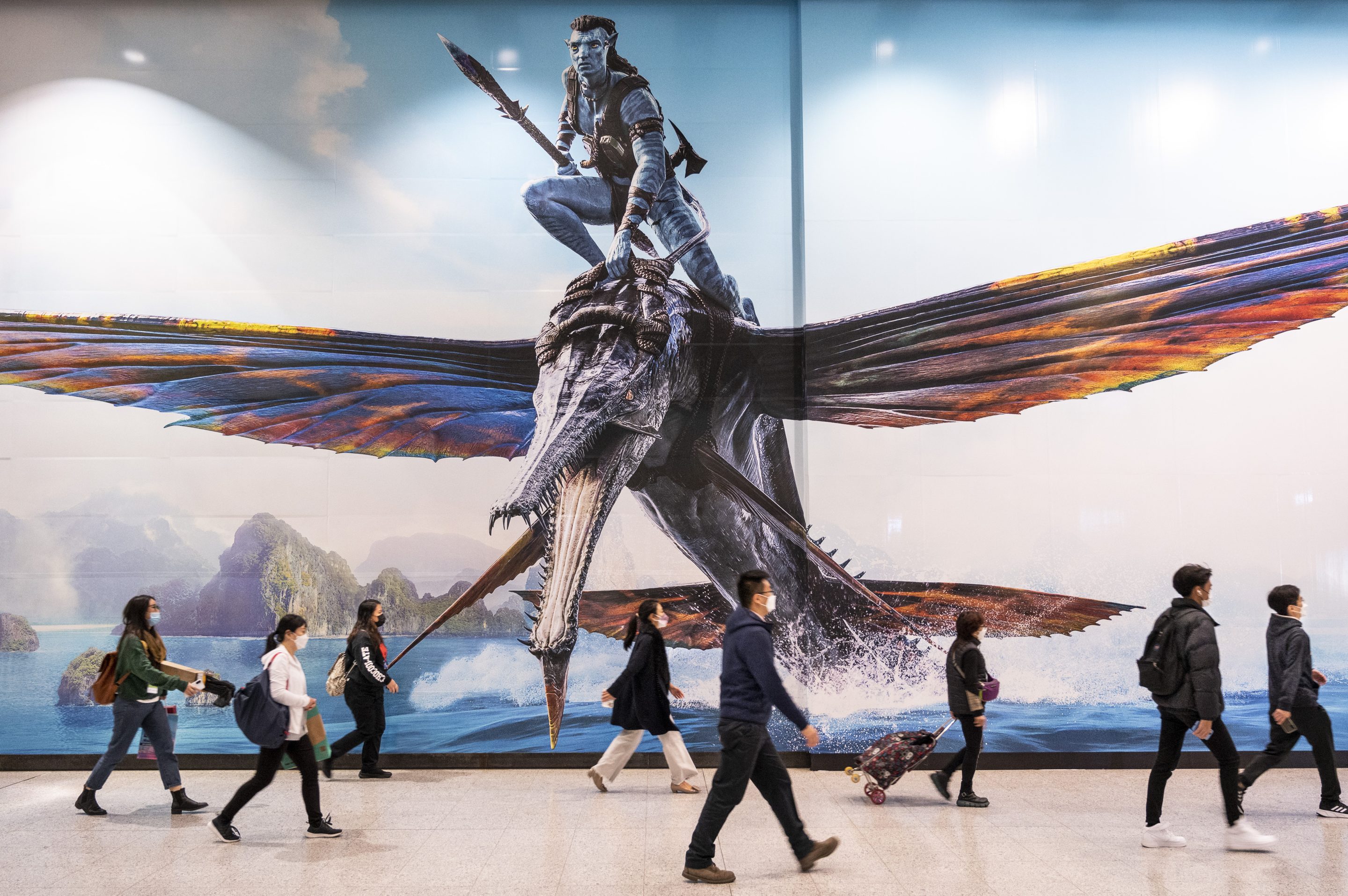 Commuters walk past a large commercial advertisement banner