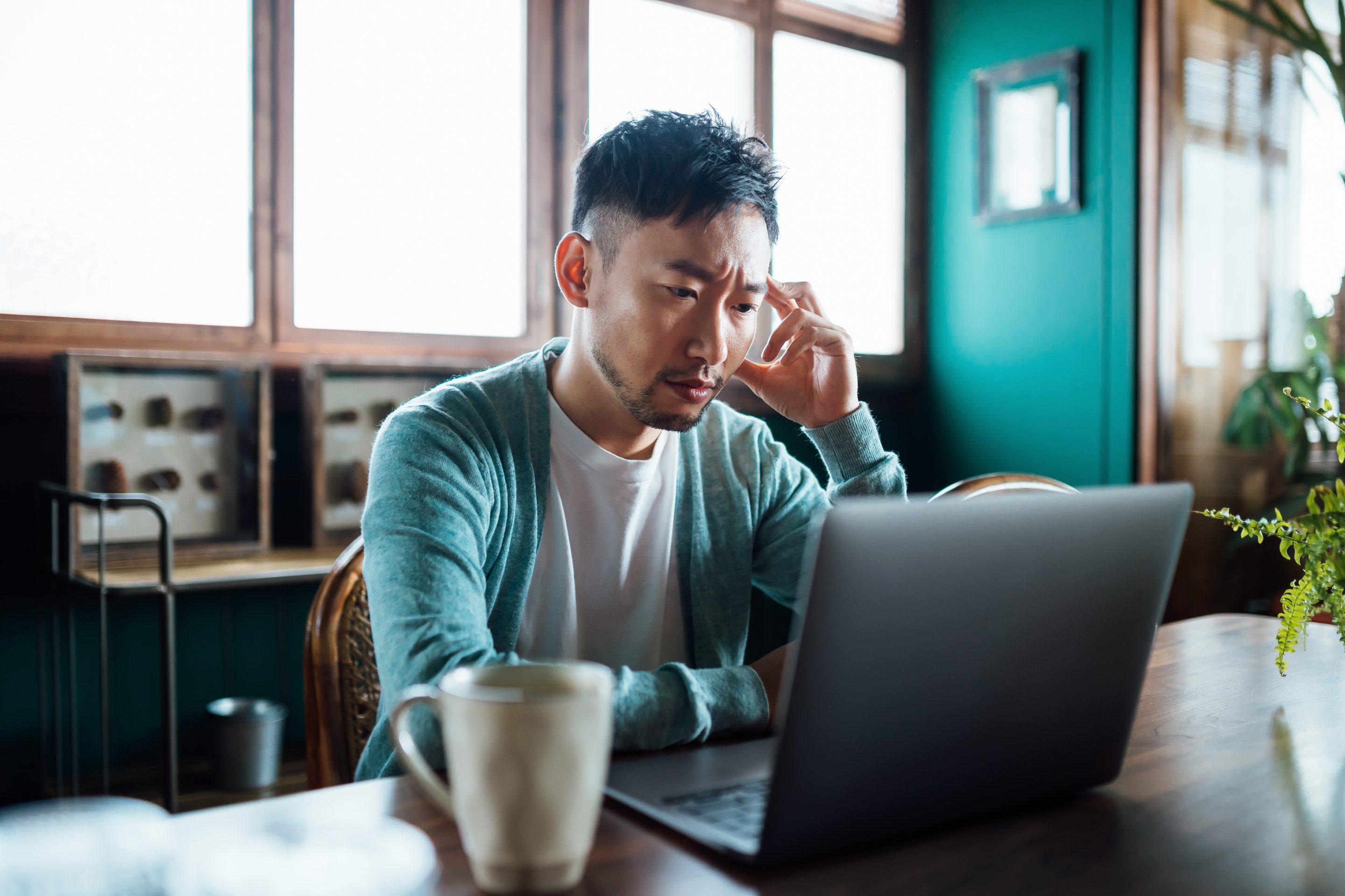 A young man looking worried on laptop