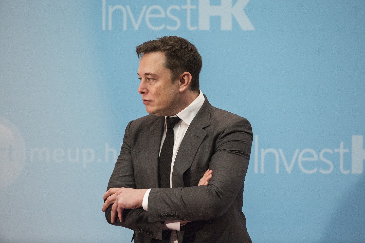 Elon Musk standing on stage with arms crossed