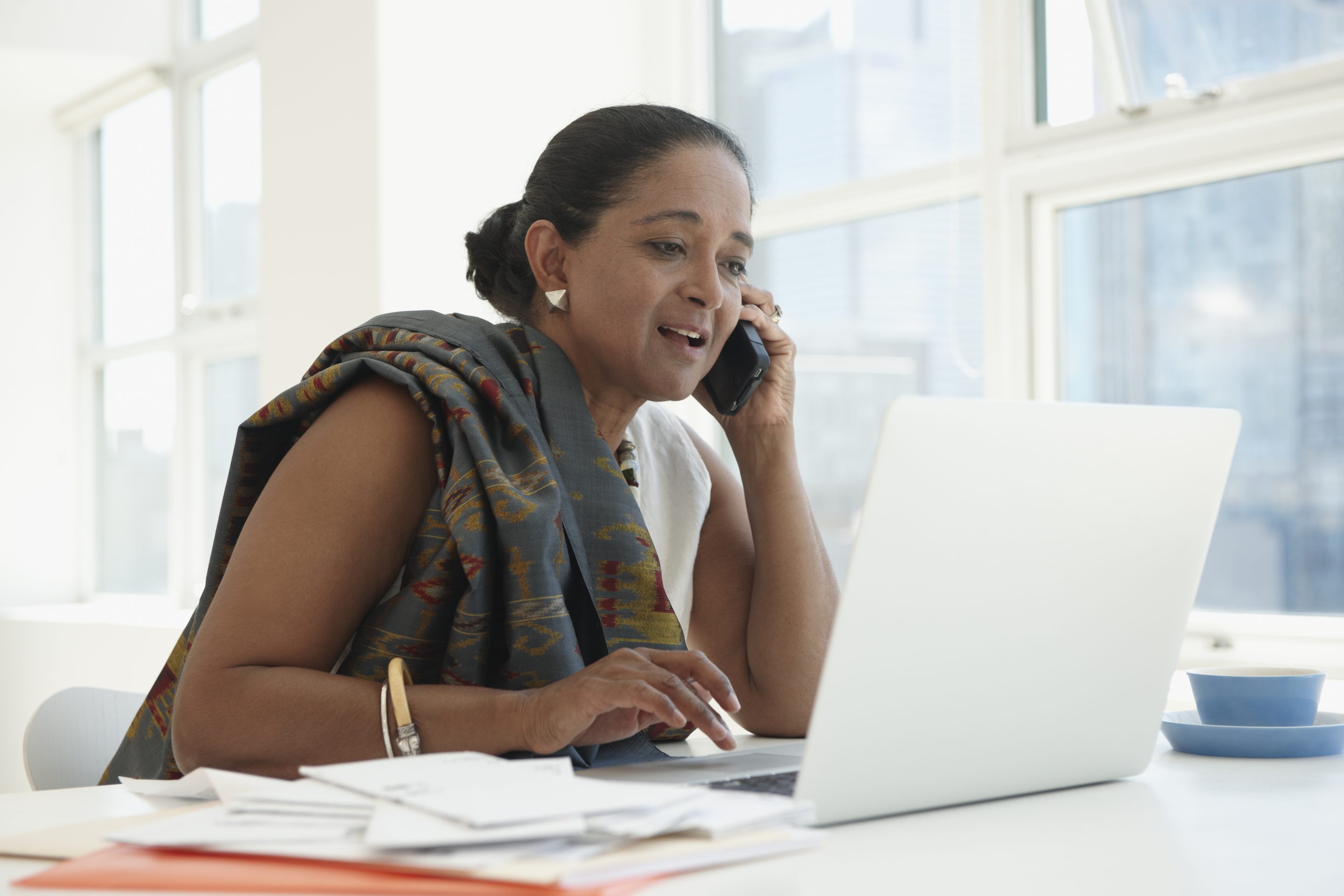 Modern Board - An older indian businesswoman sits behind a laptop