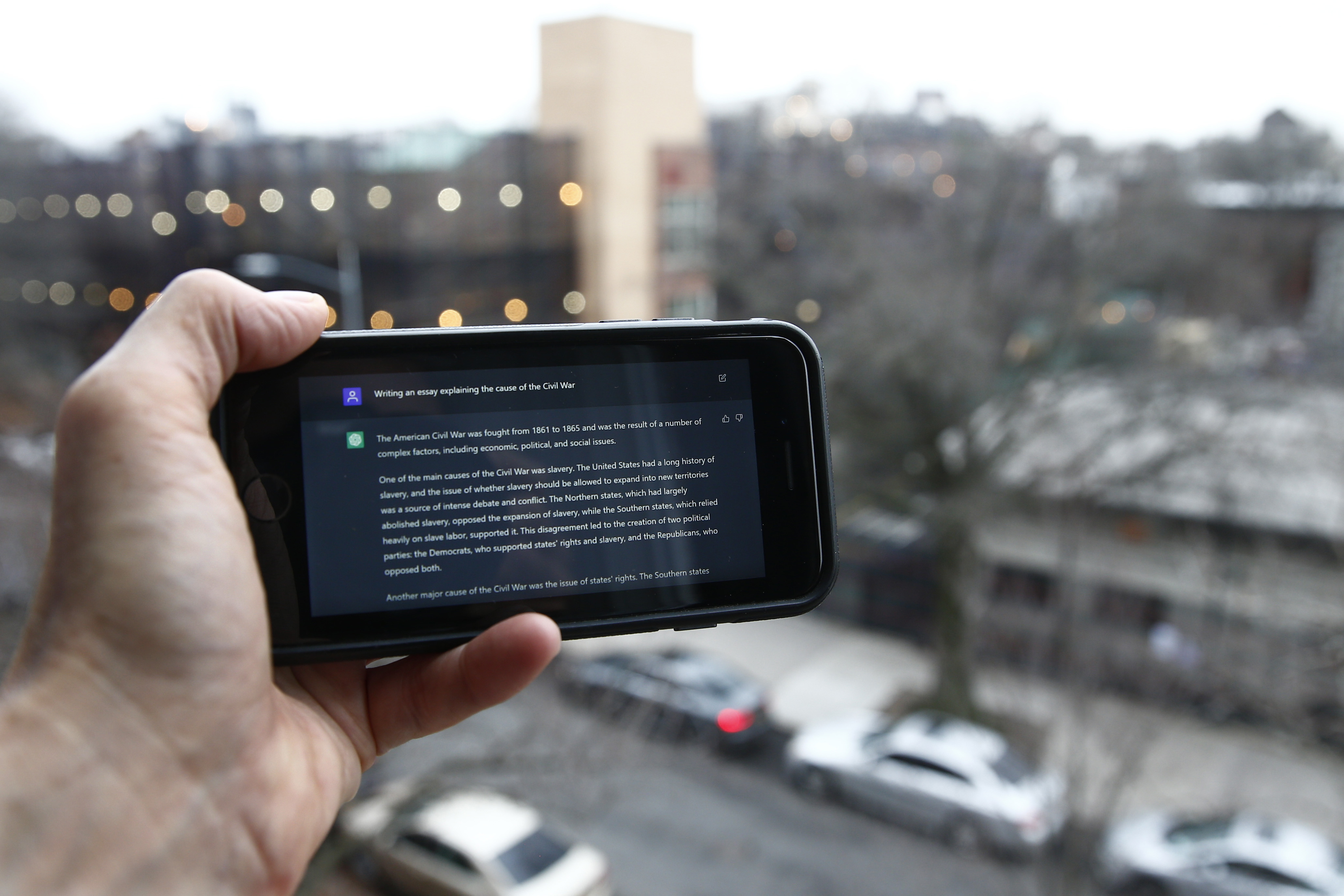 Someone holding a smart phone with a ChatGPT prompt.