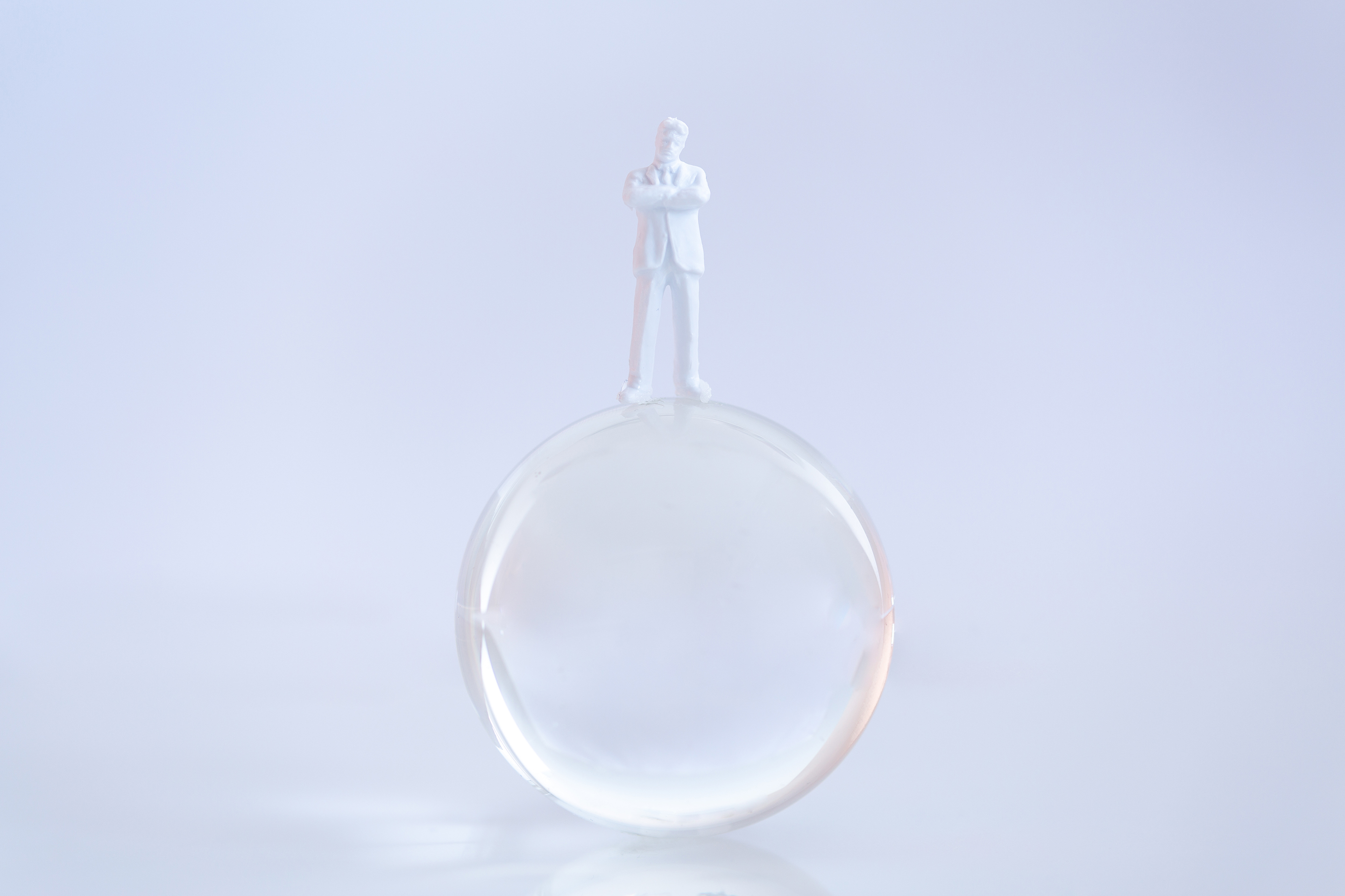 Man (white figure) balancing on a crystal ball.