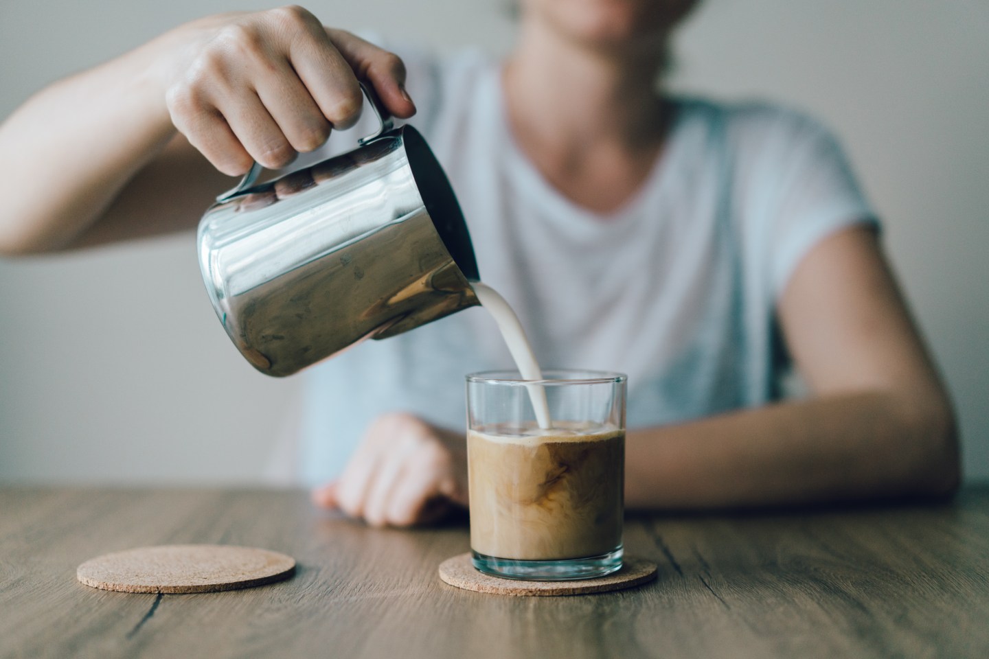 Iced coffee with milk being poured in.