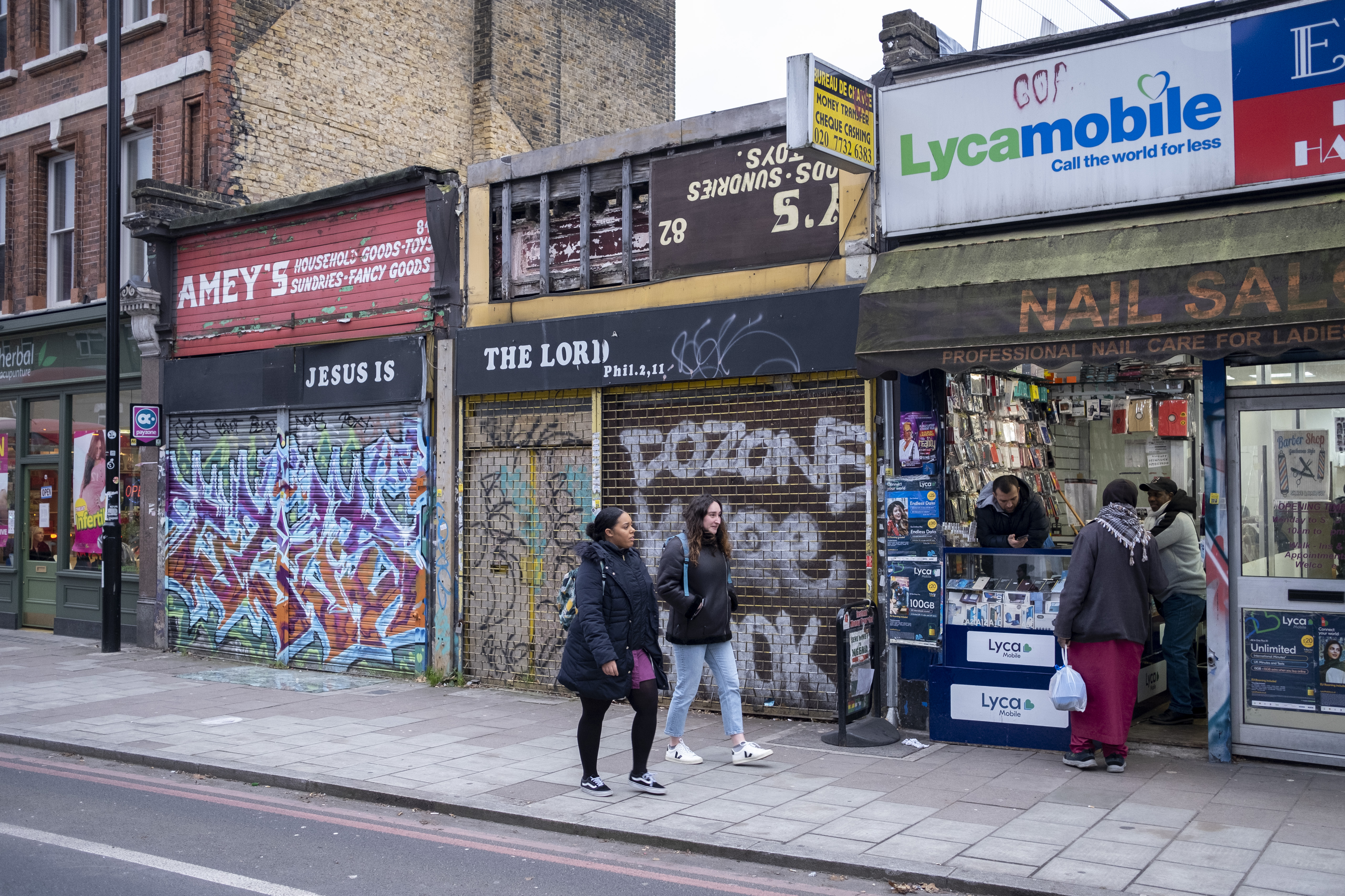 Pedestrians walk by shuttered storefronts in London.