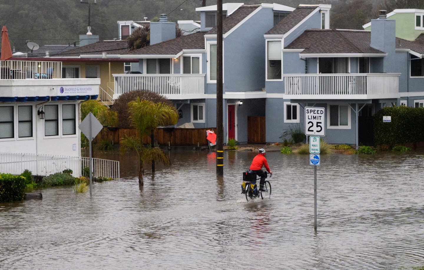 A man rides his bike through a flooded road in Aptos, California.