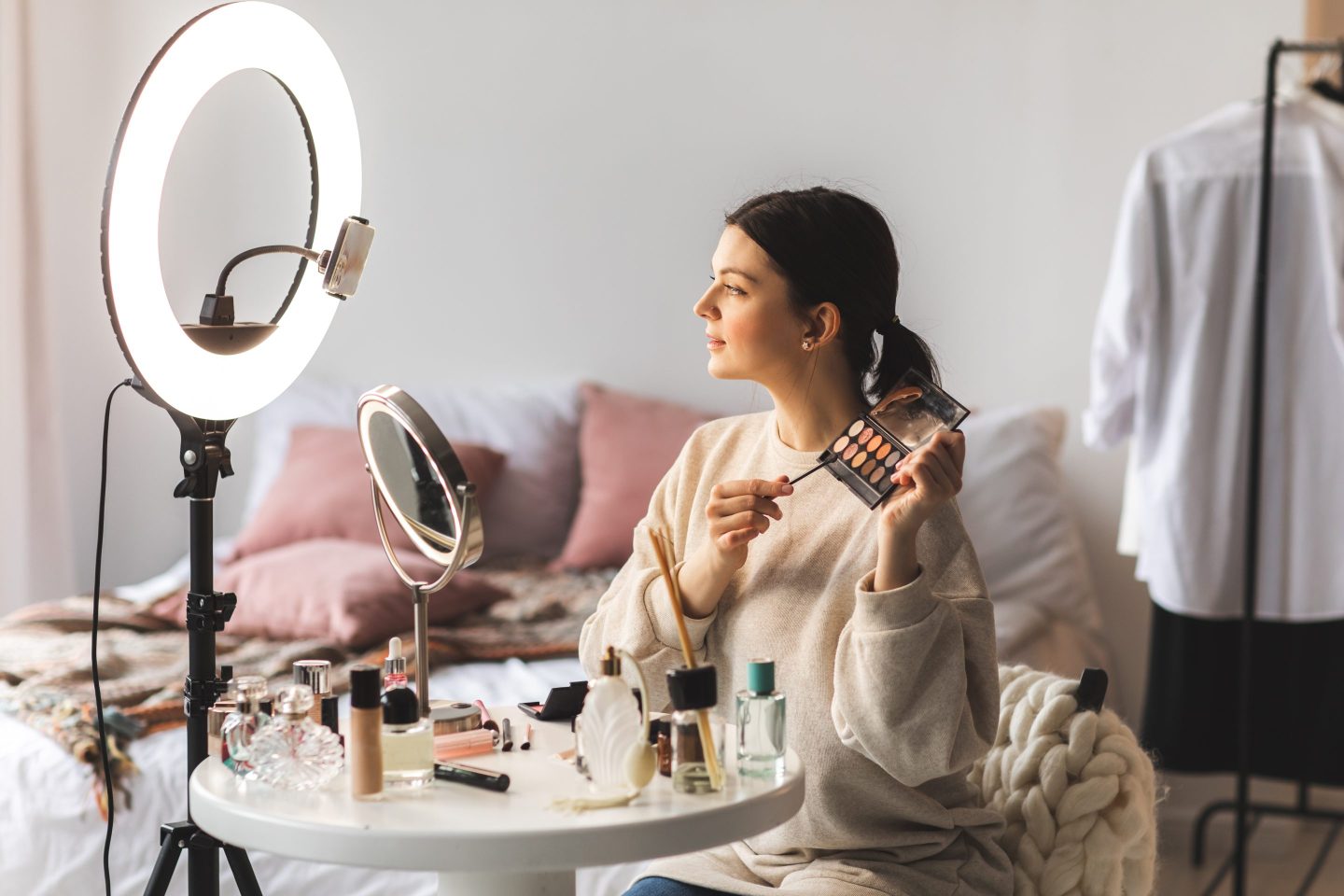 Make up artist demonstrating eye shadow palette while recording a video at home