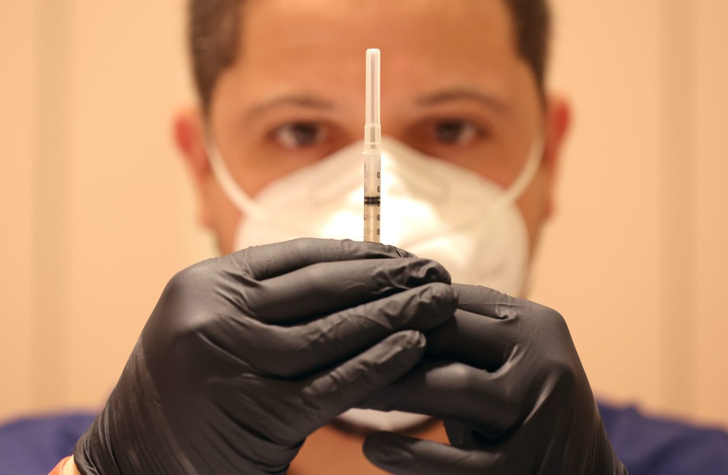 Medical professional fills a needle with COVID vaccine booster