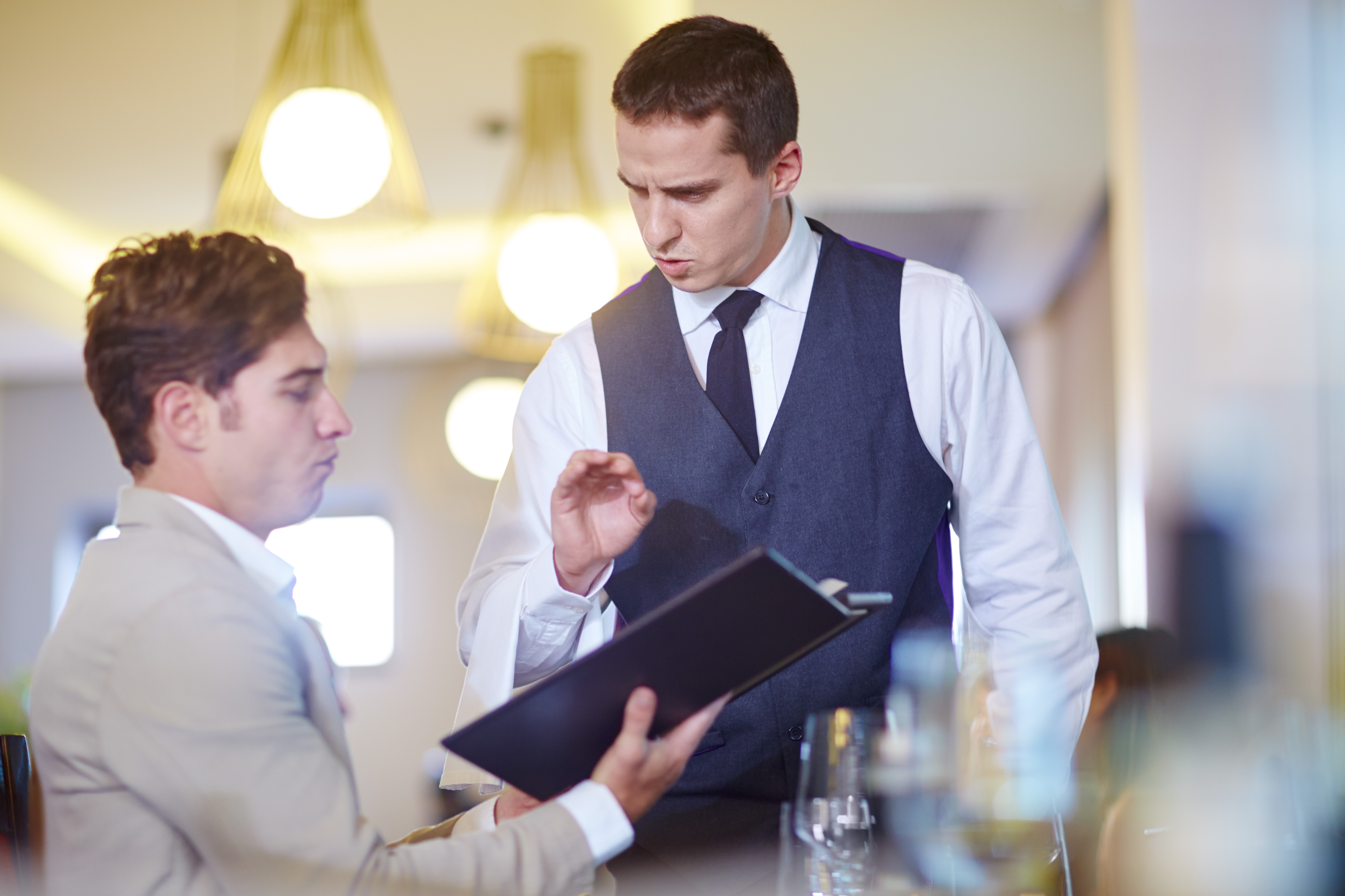 A man ordering from a waiter in a restaurant.
